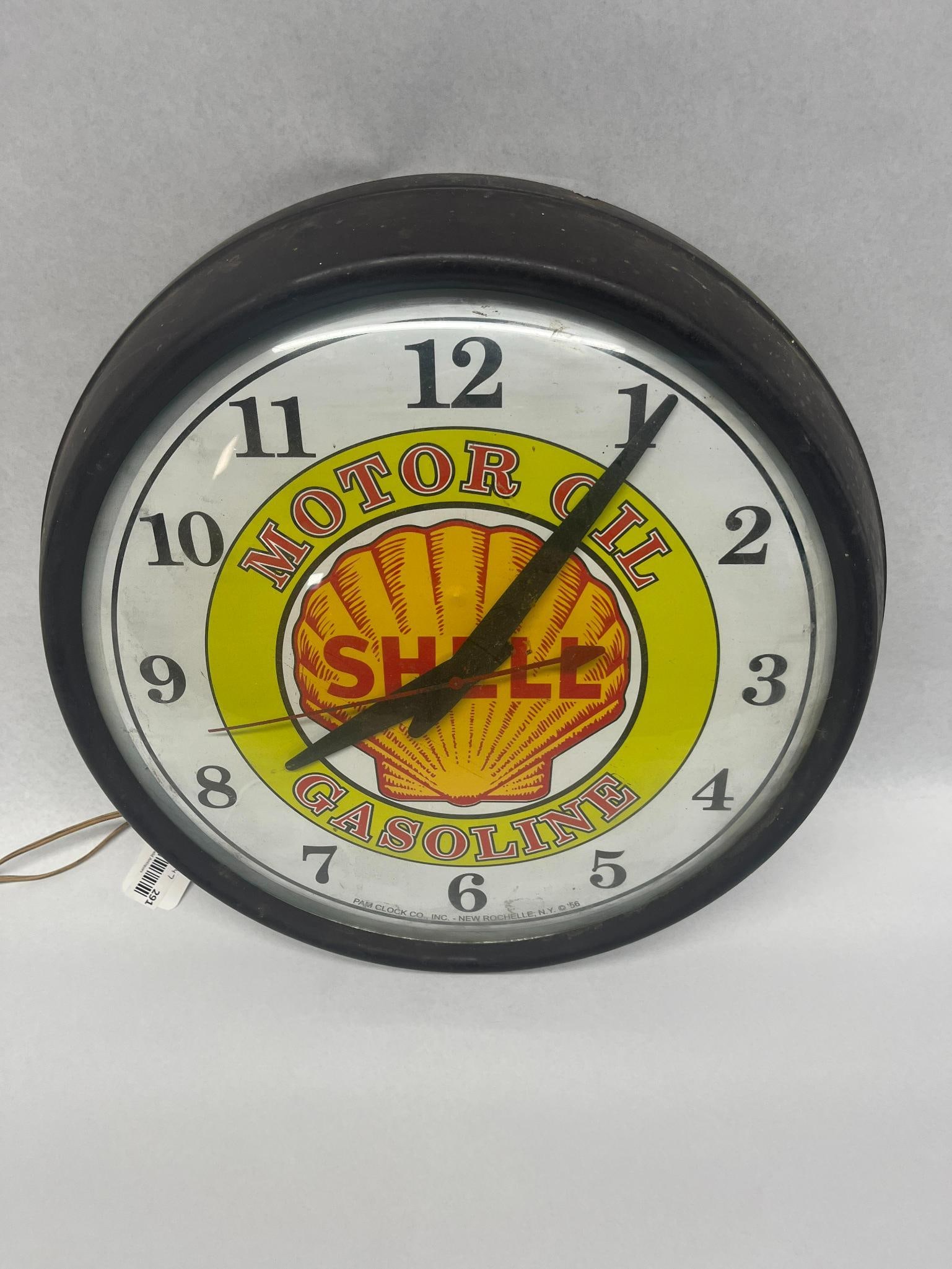 Pam Clock Co. Shell Oil & Gas Clock: An electric advertising wall clock produced for Shell Oil. The circular piece features a white dial face protected by a glass cover. The center displays the red and yellow Shell pecten logo with the b