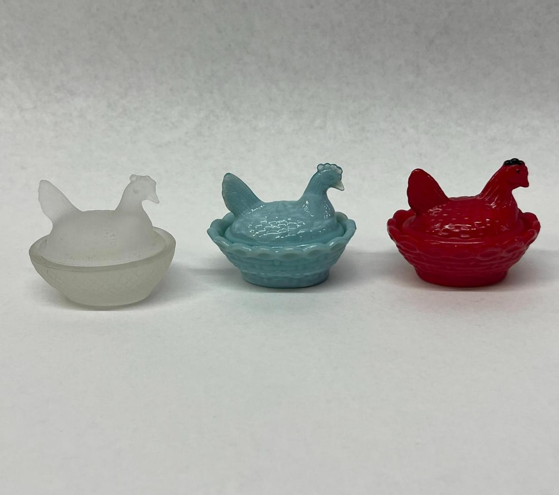 3 Westmoreland & Kemple Glass Hen Nests: A trio of miniature glass hen on nest covered dishes in various colors and glass types. The first dish is crafted from opaque light blue glass featuring a basketweave pattern nest with a scalloped rim