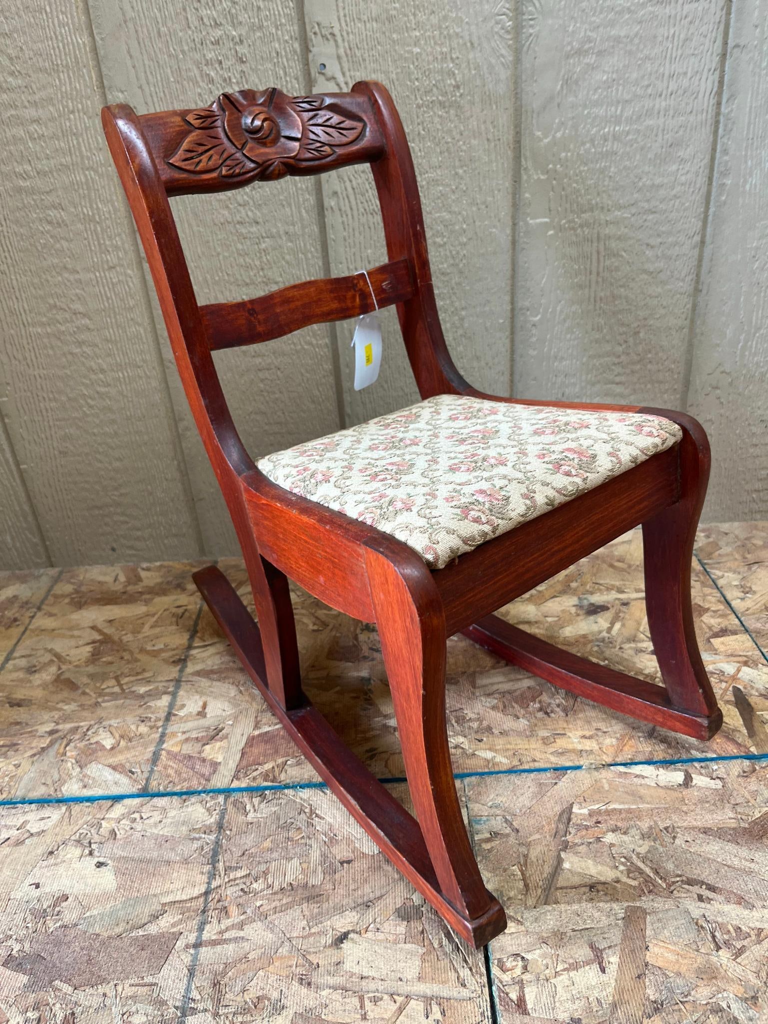 Child's Hardwood Rocking Chair w/ Rose: A child's rocking chair constructed from stained hardwood with a reddish-brown finish. The chair is supported by four legs integrated into two solid wood rockers and utilizes standard commercial
