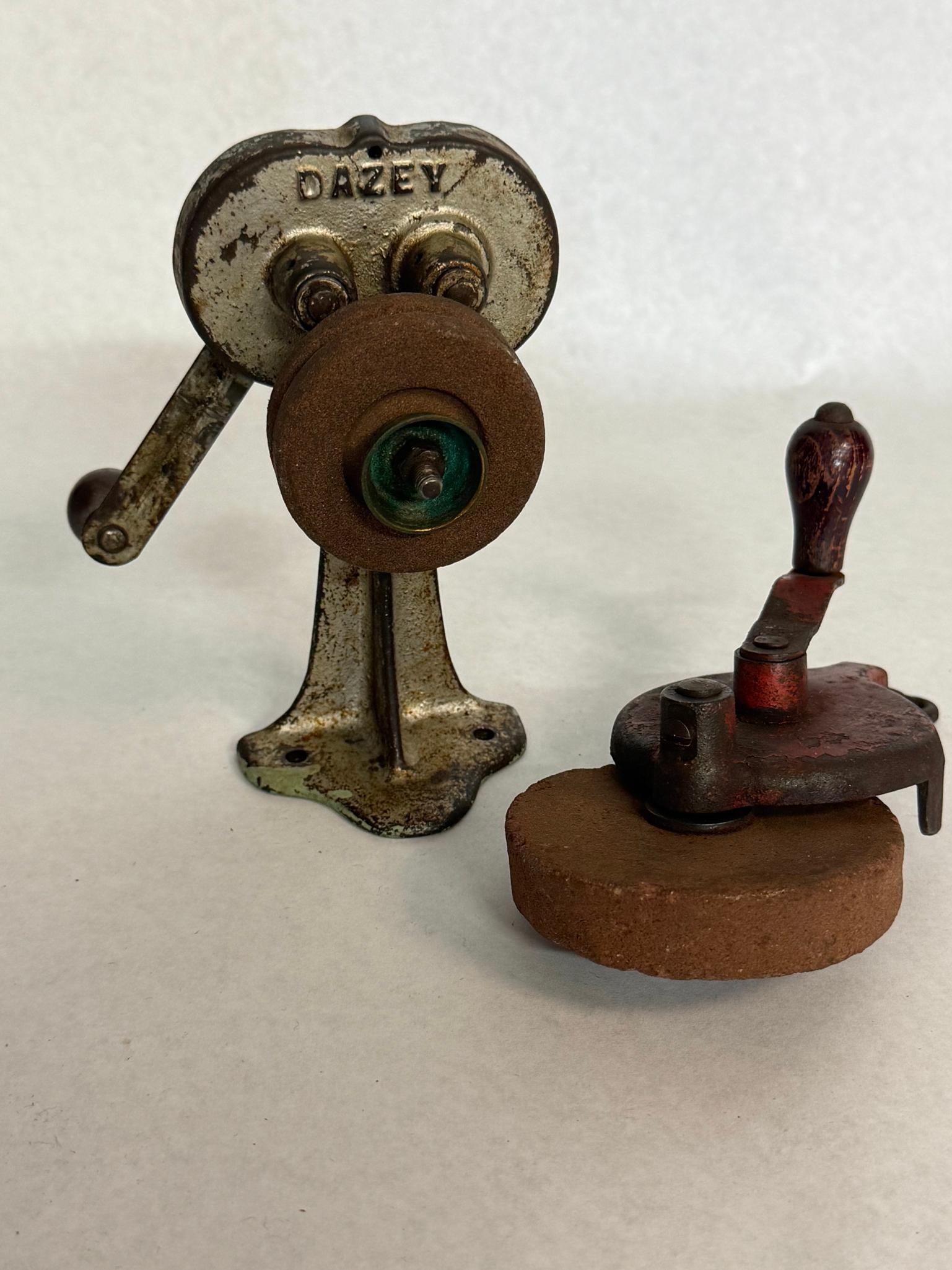 One grinder AND one Dazey Sharpener"?: Two hand-cranked sharpening tools. A circular indentation on the left side is impressed with characters reading PAT D OCT 20 1925. Along the bottom edge of the reverse side is the inscription MADE IN
