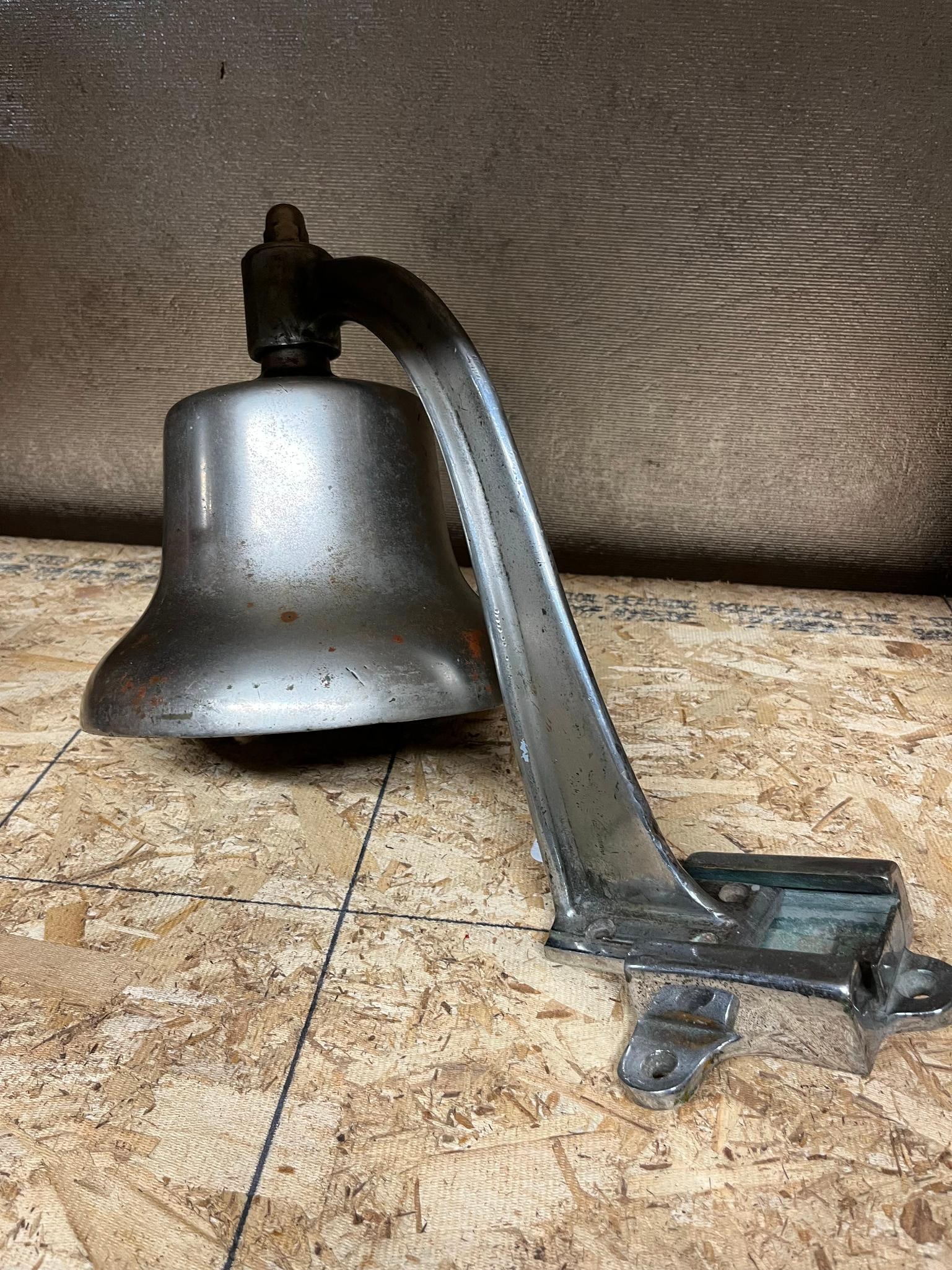 Greenberg US Navy Metal Bell w/ Bracket: A mid-20th-century American military or naval vehicle bell of cast metal construction with a dulled chrome or nickel-plated finish. The exterior body of the bell features raised cast letters reading