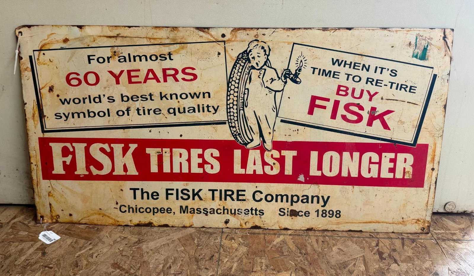 Fisk Tire Company Advertising Sign: A large rectangular horizontal advertising sign for The Fisk Tire Company. The sign is constructed from painted metal and features the brand mascot, the Sleepy Boy, depicted in footed pajamas holding 