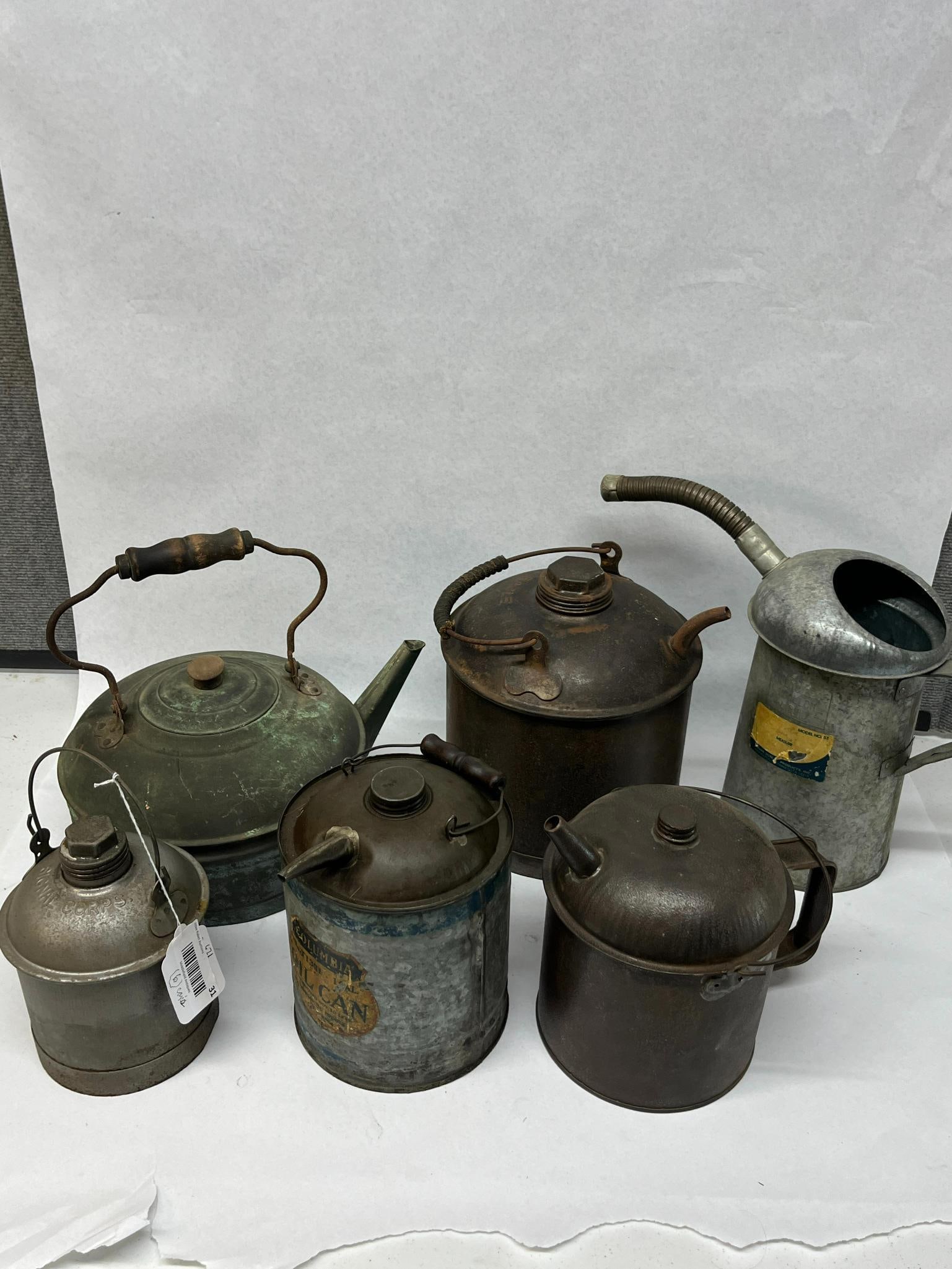 Eagle & Columbia Metal Oil Cans: A collection of metal utility containers and oil cans of various forms. One small galvanized steel canister features a wire bail handle and a hexagonal screw cap, with the text SIGNAL CORPS embossed
