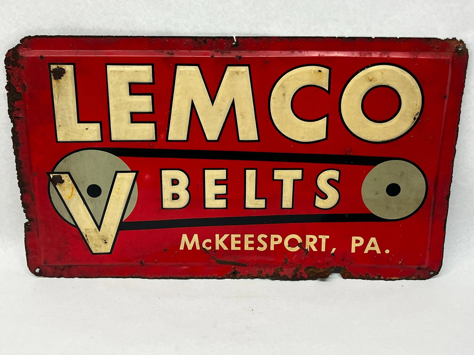 Lemco V-Belts Embossed Sheet Metal Sign: This rectangular industrial advertising sign is constructed from embossed sheet steel with a painted finish. The lower portion of the sign features the printed text McKEESPORT, PA. A small maker mark