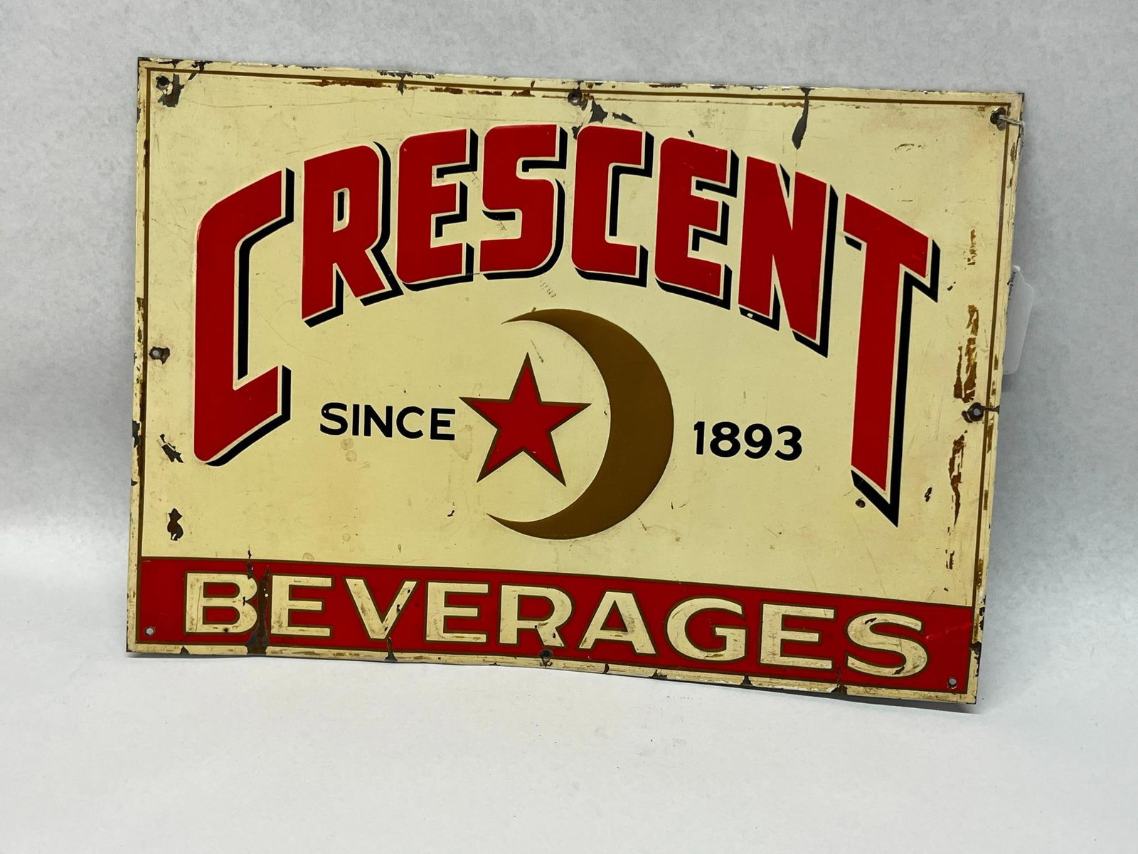 Crescent Beverages Advertising Sign: This is a single-sided metal advertising sign for Crescent Beverages. Centered below the name is a graphic logo comprising a metallic gold-tone crescent moon surrounding a red five-pointed star. The