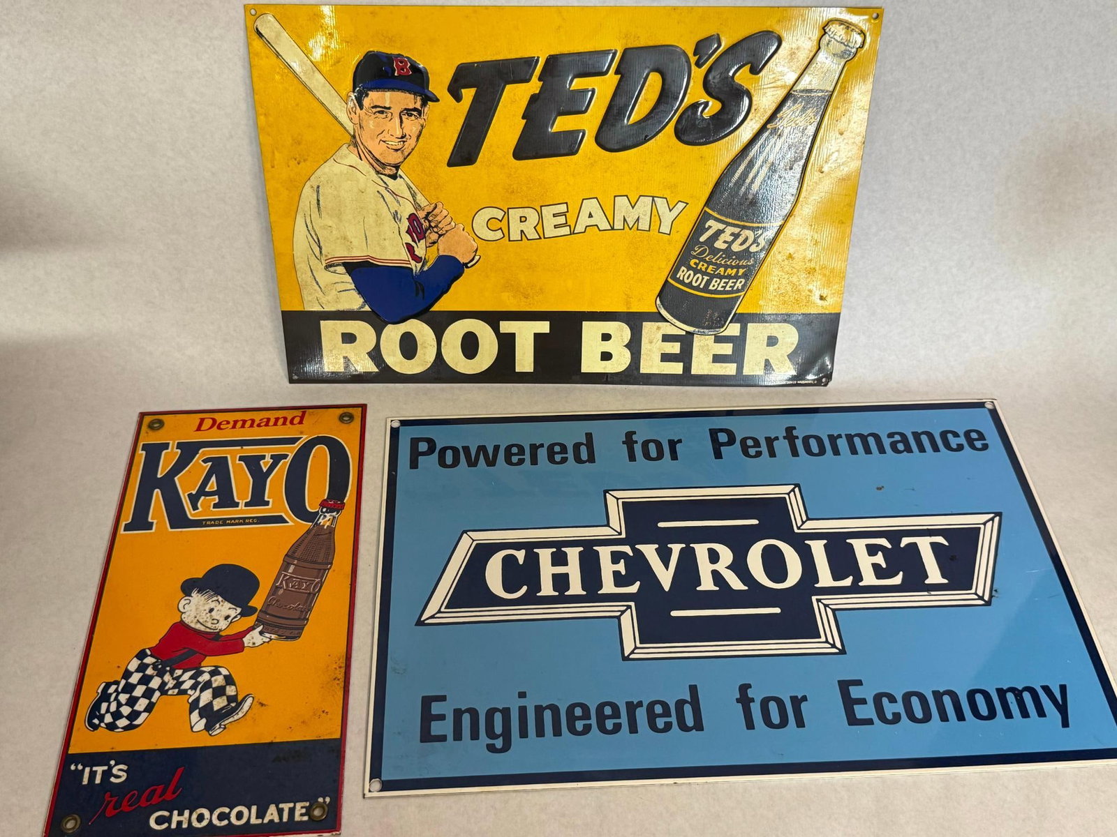 3 Ted's, Kayo & Chevrolet Metal Signs: A trio of metal advertising signs featuring beverage and automotive branding. A copyright mark at the bottom left reads ? DESPERATE SIGN CO. and a second mark at the bottom right reads ? CO-ORDINATED 