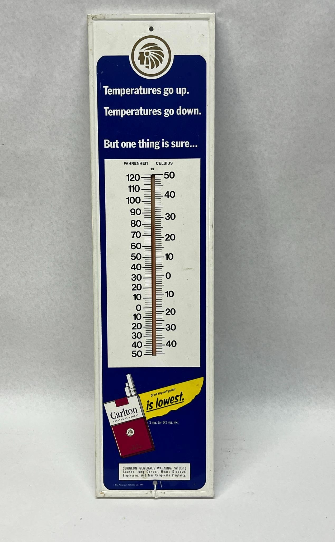 Carlton Cigarettes Thermometer 1991: A vertical advertising wall thermometer for Carlton cigarettes constructed of painted metal. The sign features a blue and white color scheme with a central recessed channel containing a glass
