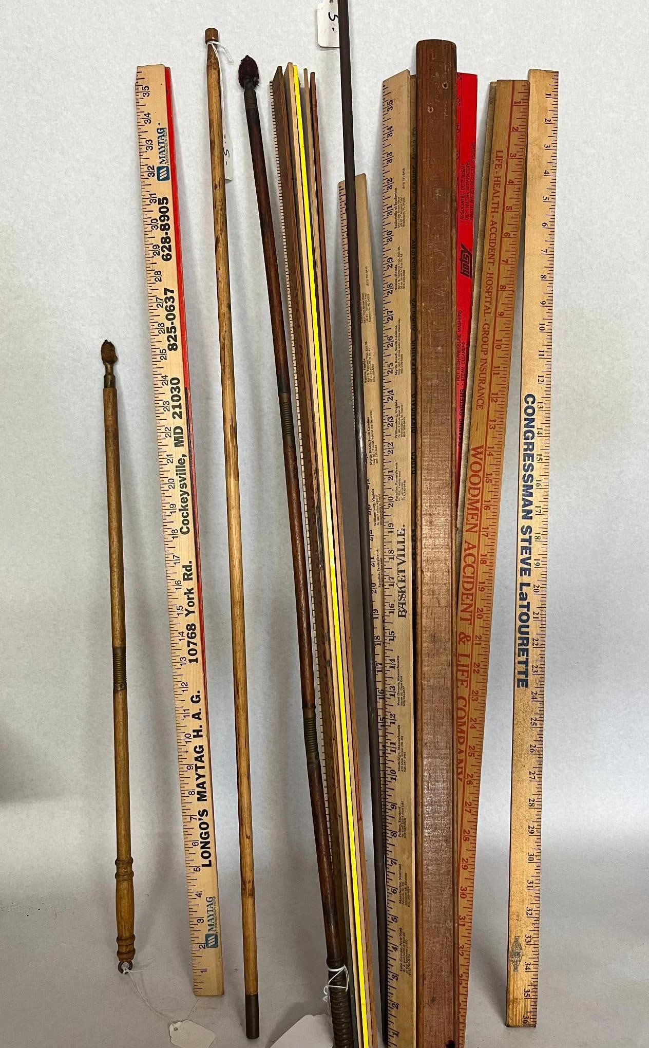 Advertising Wood Yardsticks & Rods: A group of advertising and commemorative wooden yardsticks together with several wooden rods. One natural wood yardstick is printed in black and red with a Maytag logo and text reading LONGO'S MAYTAG 