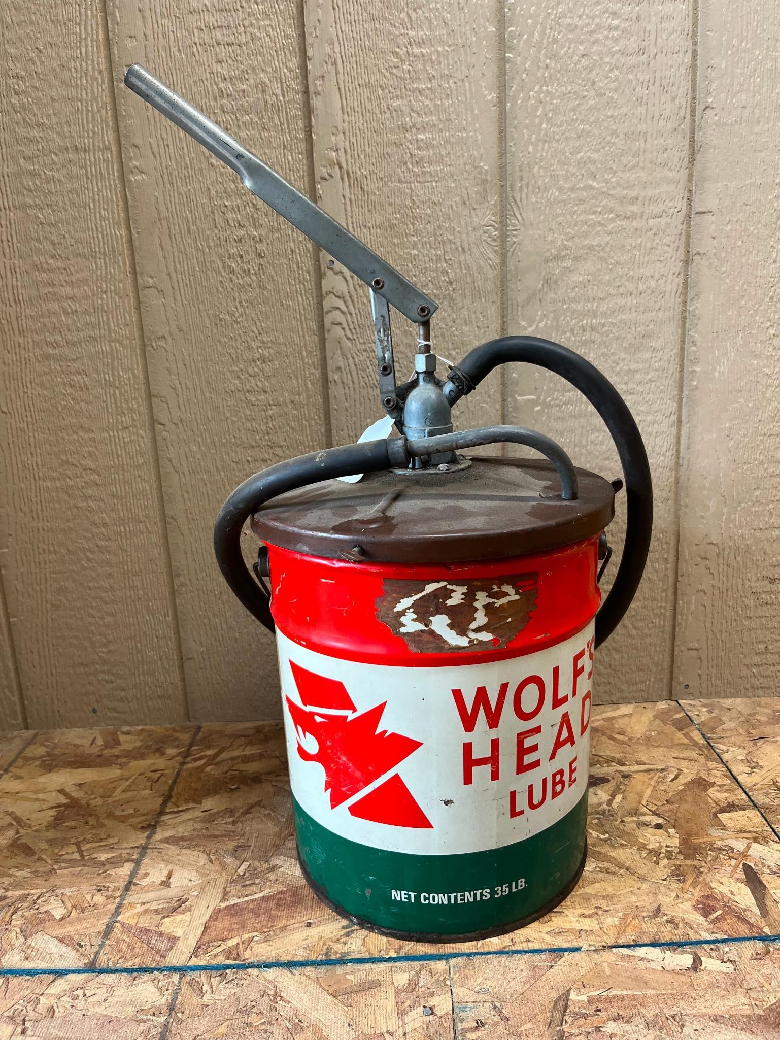 Wolf's Head Lube 35 Lb. Pail with Integrated Manual Pump: A metal lubricant pail featuring branding for Wolf's Head Lube. The container is constructed of lithographed tin with a tri-color design consisting of a red upper band, a white center band, and a
