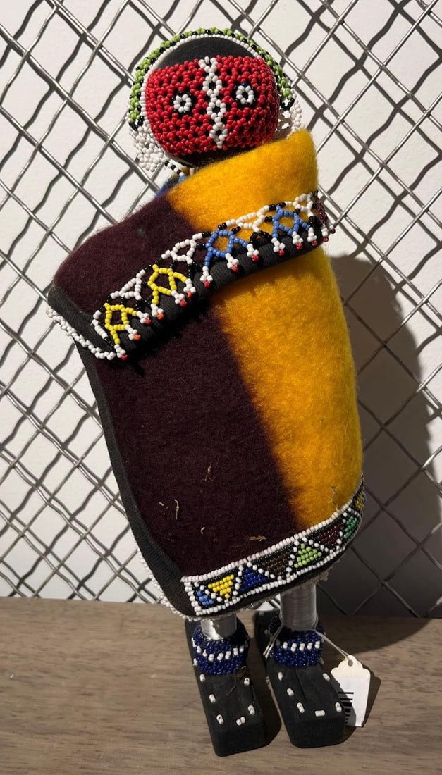 Ndebele Beaded Cloth Figure: This large-scale figurative doll is crafted in the traditional style of the Ndebele people of South Africa. The figure is constructed with a black fabric-covered head featuring a prominent circular be