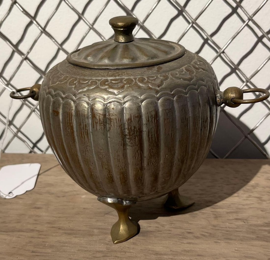 Lobed Silver Plated Tripod Jar w/ Rings: A decorative lidded vessel featuring a globular body with hand-hammered vertical lobing. The shoulder of the jar is decorated with a repousse band of foliate and floral motifs. The body and lid are co