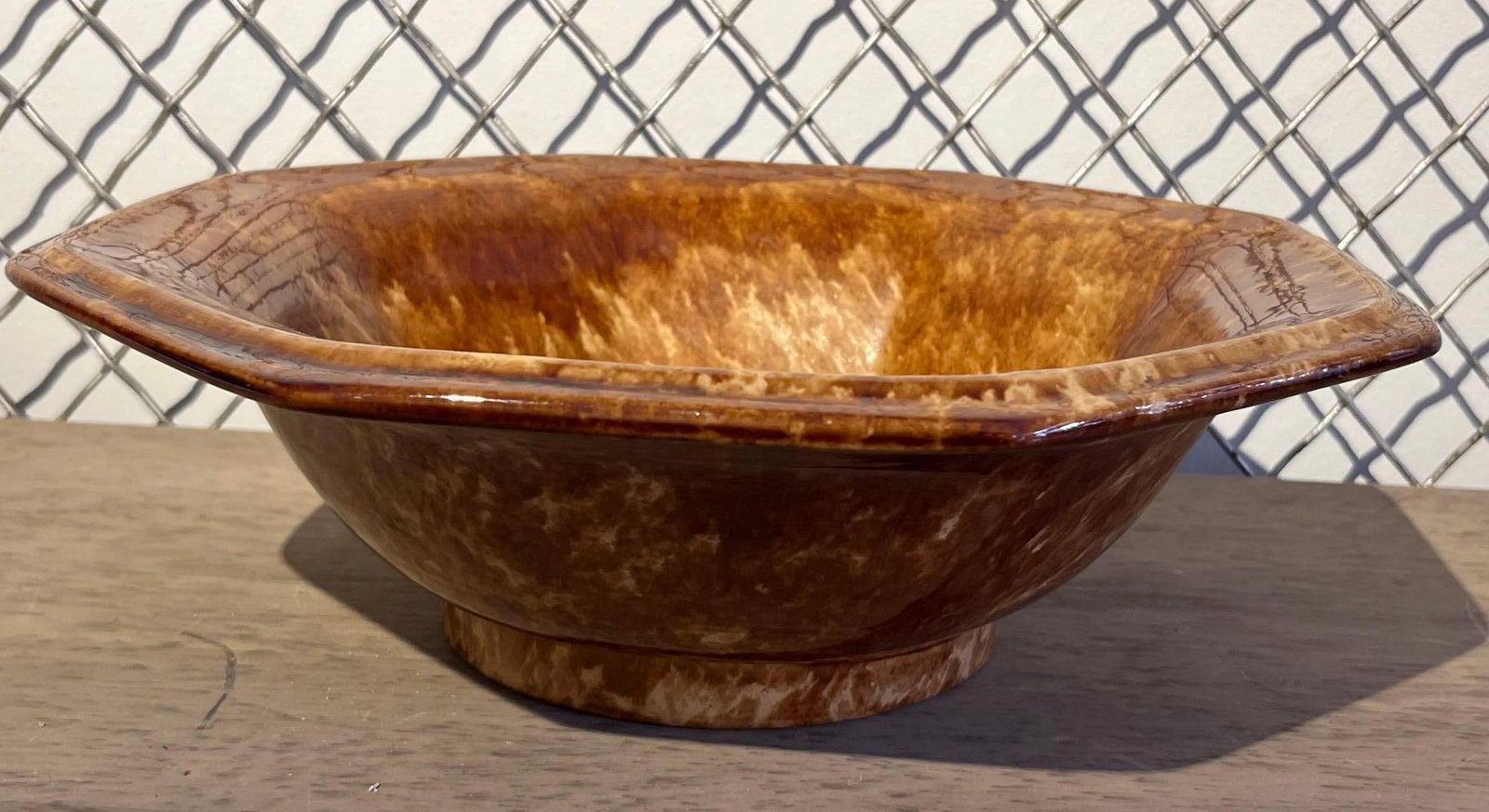 Rockingham Octagonal Yellowware Bowl: An octagonal serving bowl constructed from yellowware earthenware. The vessel features a flared eight-sided rim and is supported by a circular raised foot. The piece is decorated with a mottled Rockin