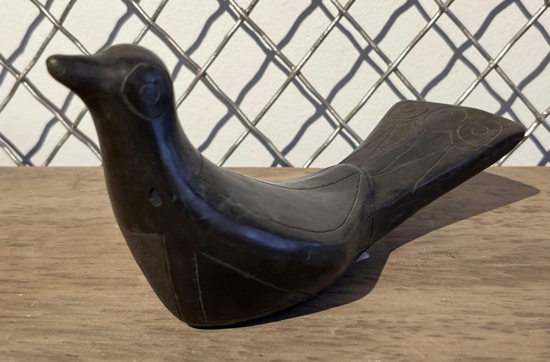 Mexican Blackware Bird Sculpture: A stylized bird sculpture crafted from burnished black pottery. The figure features a simplified, modern form with a smooth, dark polished exterior. Incised decorative lines define the wings and body,