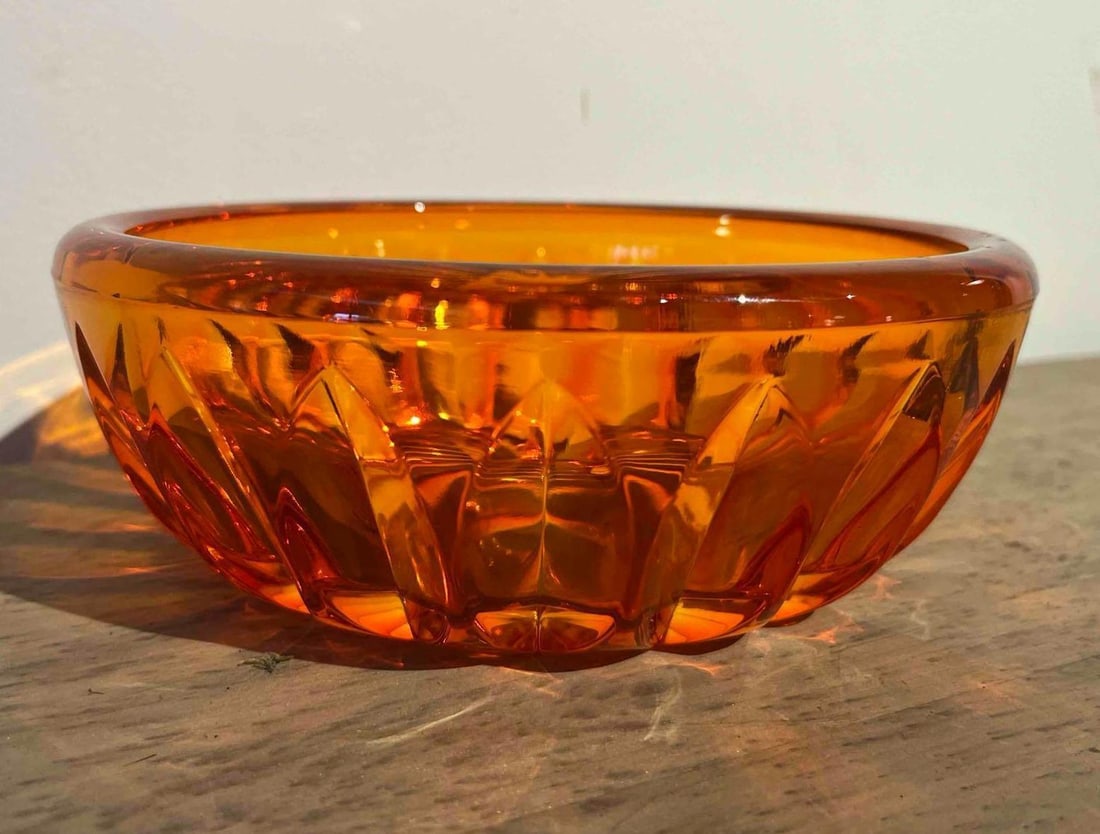Mid-Century Amber Glass Geometric Bowl: A heavy pressed-glass bowl in a translucent amber color. The circular form features a repeating pattern of deep vertical faceted wedges around the exterior body, creating a diamond-like texture. The