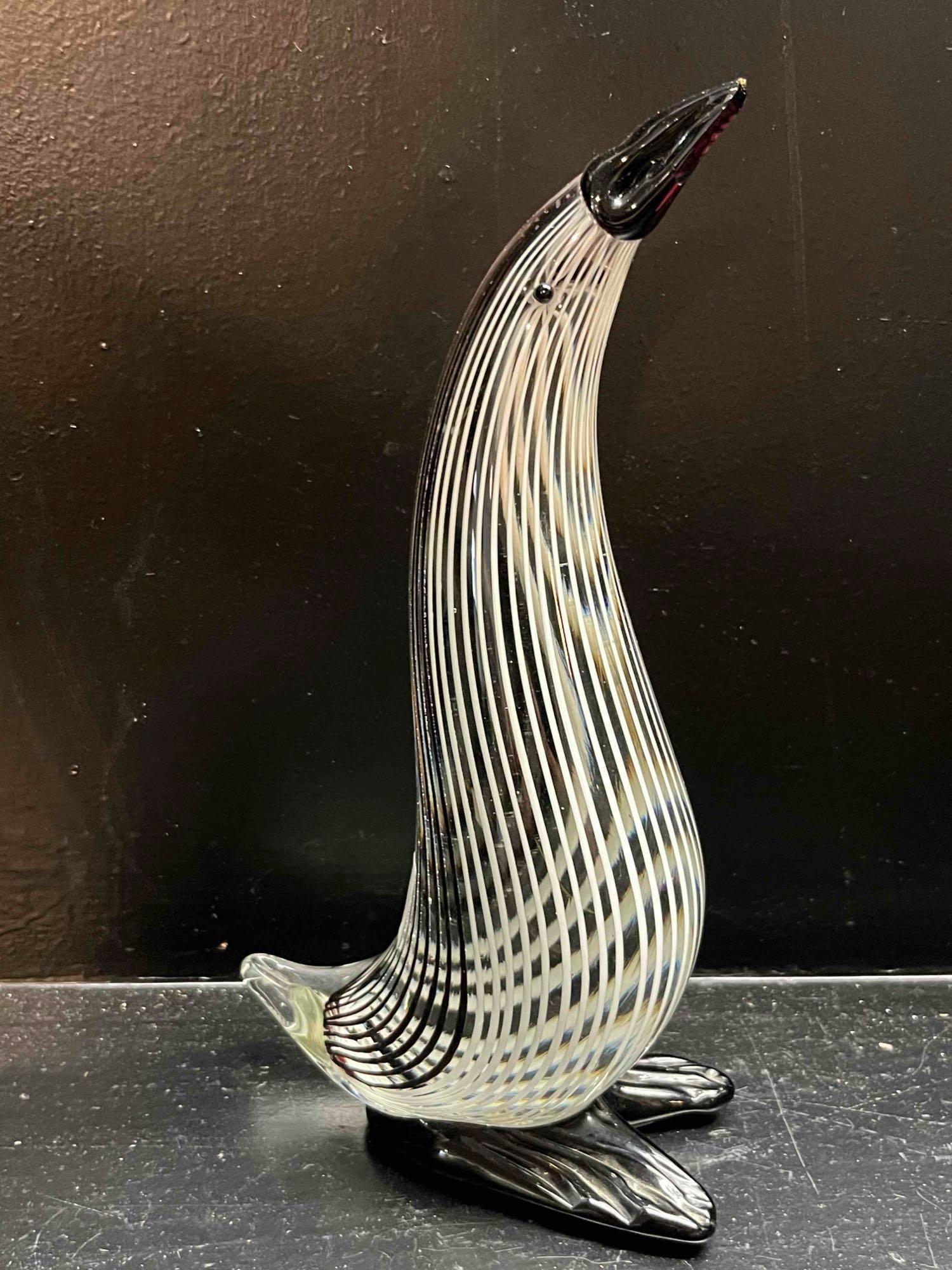 Stylized Black and White Filigree Glass Penguin Figurine: A hand-blown art glass figurine depicting a stylized penguin with an elongated neck. The torso is decorated with internal vertical black and white glass filigree canes, a technique known as