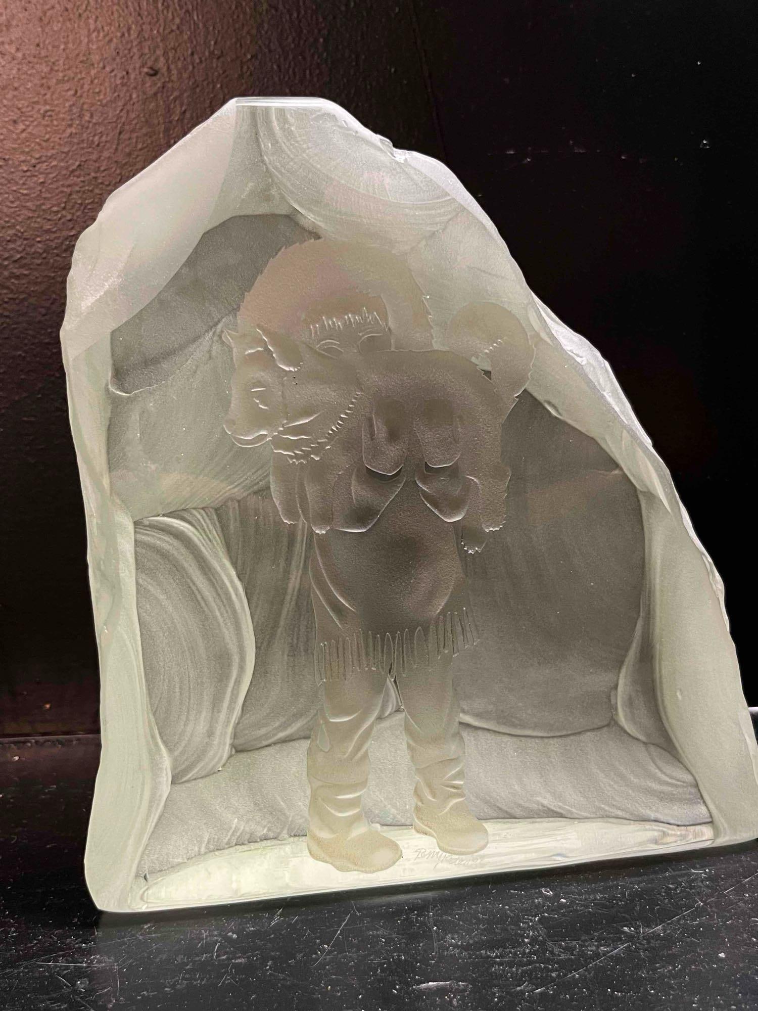 Tompkins Intaglio Glass Inuit & Husky: A three-dimensional art glass sculpture featuring an Inuit child in a traditional fringed parka holding a husky puppy. The piece is constructed from a solid block of glass with a polished flat front f
