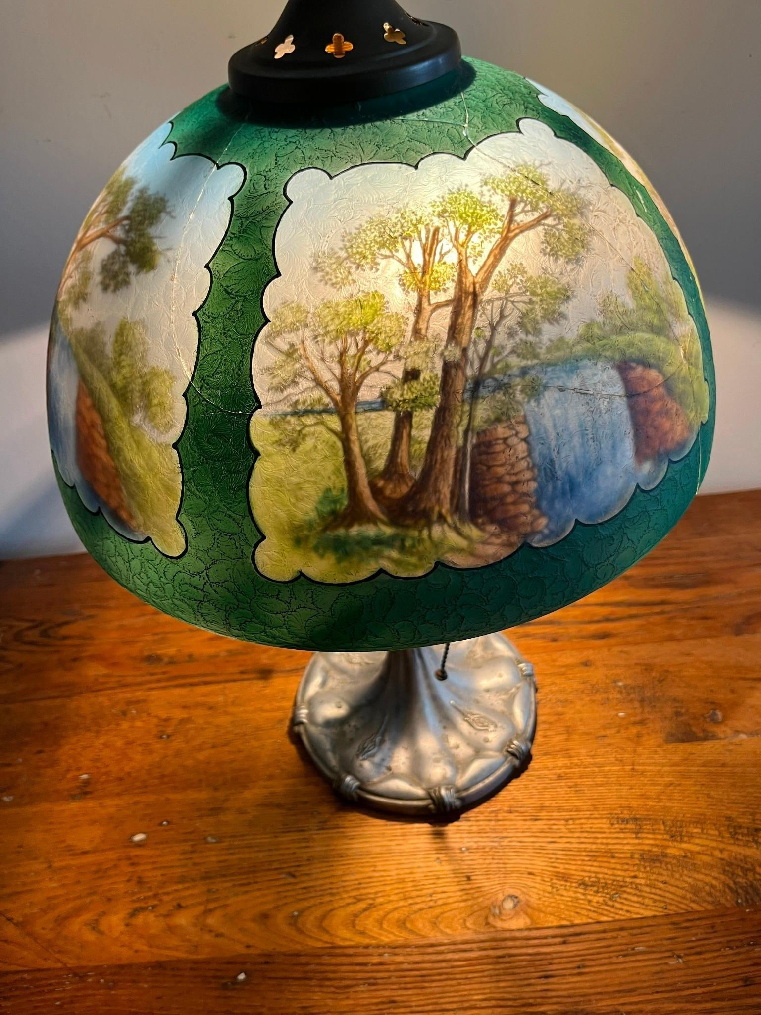 Reverse Painted Scenic Glass Table Lamp: A table lamp featuring a domical glass shade with a textured acid-etched exterior. The interior of the shade is reverse-painted with four separate landscape reserves depicting trees, rocks, and water,