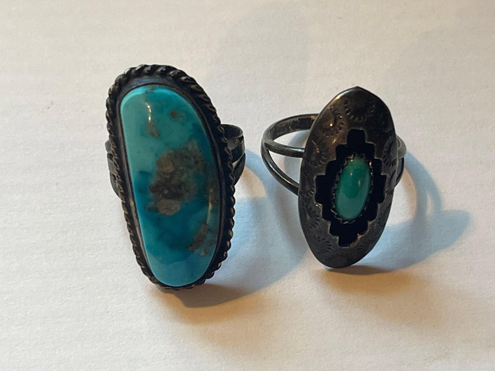 Two Southwestern Silver and Stone Rings: This lot comprises two Southwestern-style rings featuring traditional metalwork and cabochon settings. The first ring is a statement piece featuring a large, elongated oval turquoise cabochon with a l
