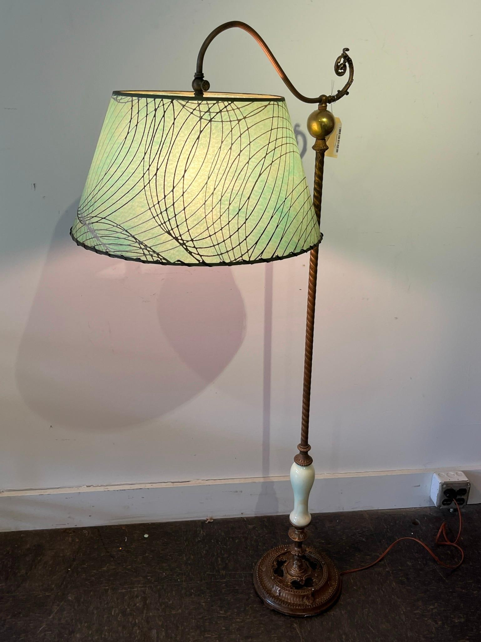 Cast Metal Bridge Lamp w/ Uranium Glass: This floor lamp features an ornate cast metal base and a curved bridge arm. The base is circular with pierced scroll and leaf motifs, supporting a central stem with a twisted metal pole. An elongated,