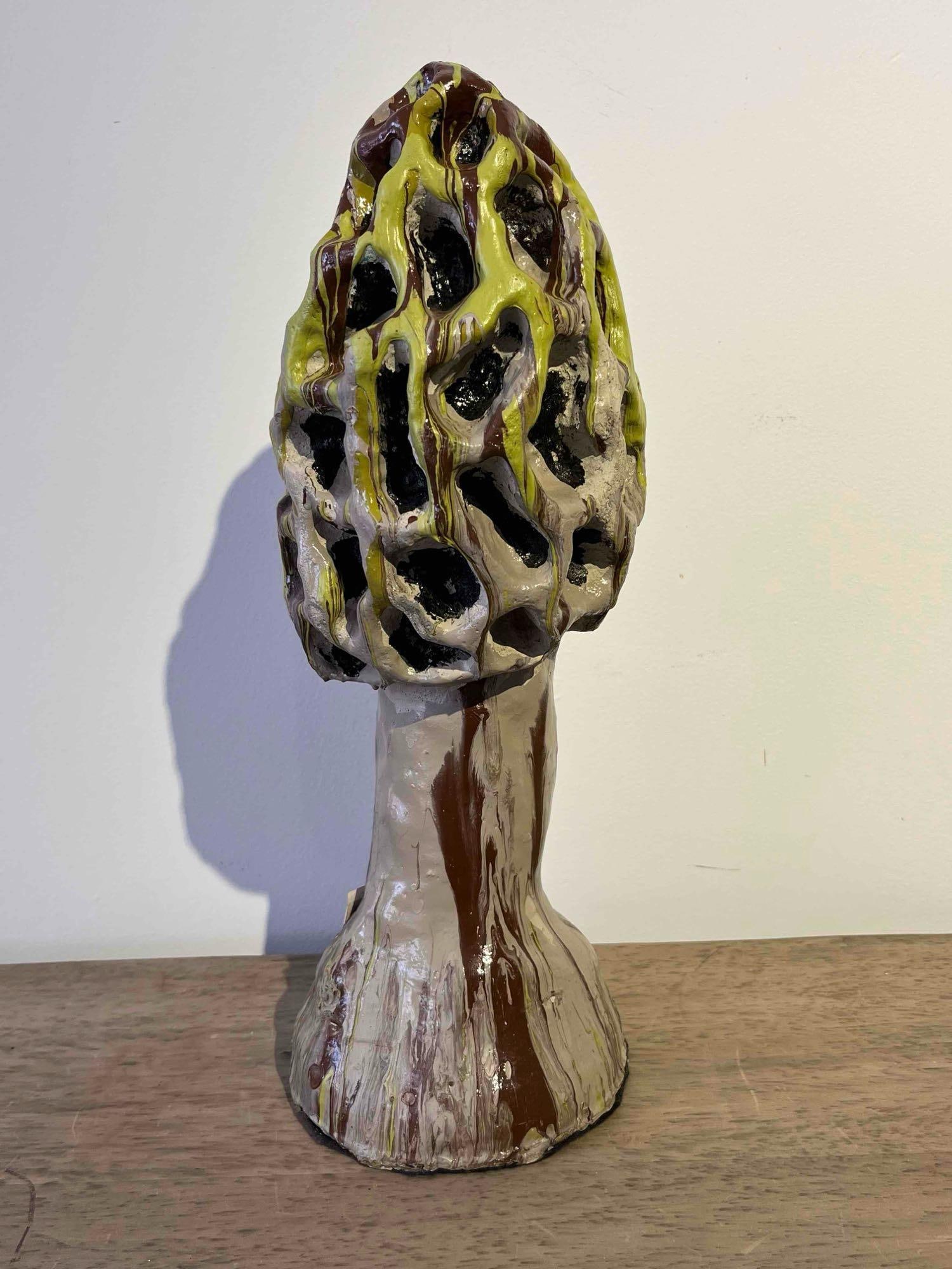 Studio Pottery Morel Mushroom Sculpture: This ceramic sculpture depicts a stylized morel mushroom featuring a hollow cap with a deeply pitted, honeycomb texture and a thick, flared stalk. The exterior is finished in a glossy, multi-tonal dri