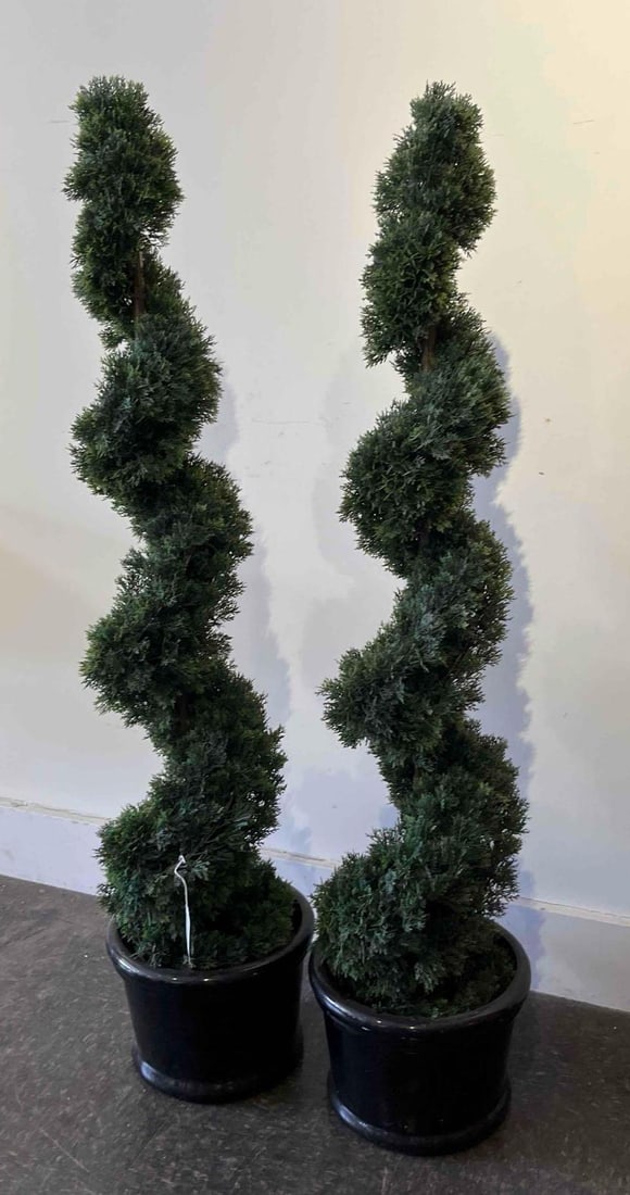 Pair Artificial Spiral Topiary Trees: A matched pair of floor-standing artificial topiary trees. Each piece is constructed with synthetic evergreen foliage arranged in a continuous spiral form around a central natural wood trunk. The