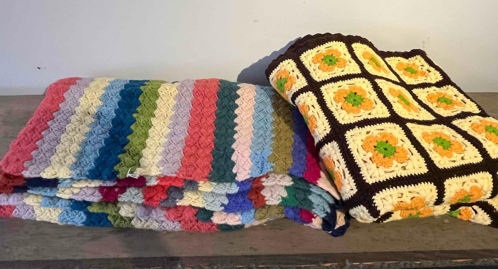 A Pair of Crocheted Afghans: Two hand-crocheted afghan throw blankets. The first is a rectangular throw worked in a diagonal block stitch, also known as corner-to-corner. The pattern consists of repeating diagonal stripes in a