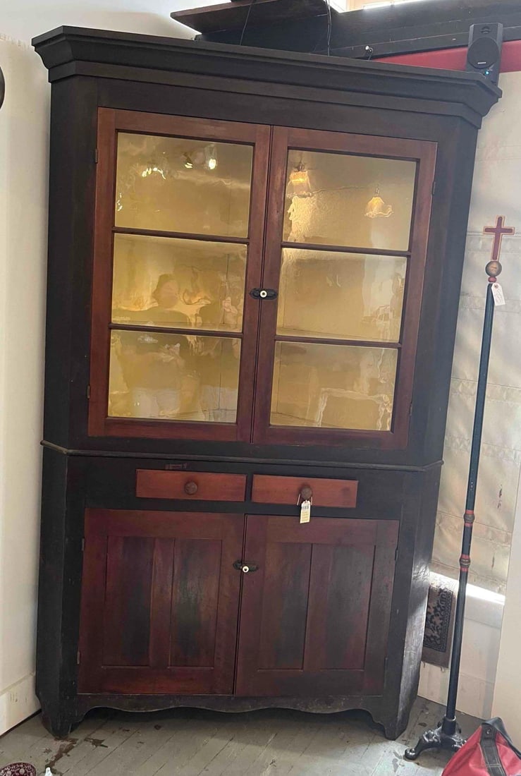 American Painted 2-Part Corner Cupboard: This American Country style corner cupboard is of two piece construction and is likely crafted from pine or a similar softwood. The exterior features a dark, near black charcoal painted or stained