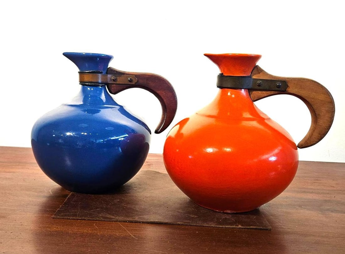 Pair Mid-C. Wood-Handle Ceramic Carafes: A pair of glazed earthenware carafes. Each vessel features a bulbous body and a tapered neck flaring to a pinched spout. One carafe is finished in a high-gloss cobalt blue glaze with a matching blue i