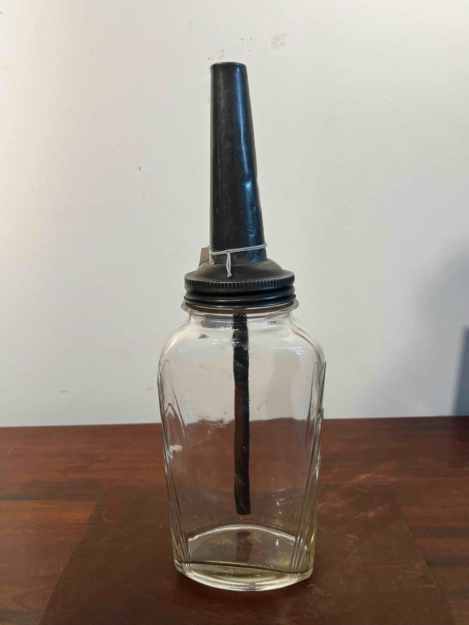 Glass Oil Bottle w/ Metal Spout: This oil dispenser bottle consists of a clear molded glass vessel with a rectangular footprint and rounded corners. Each of the four sides features an Art Deco-style relief pattern of three concentric