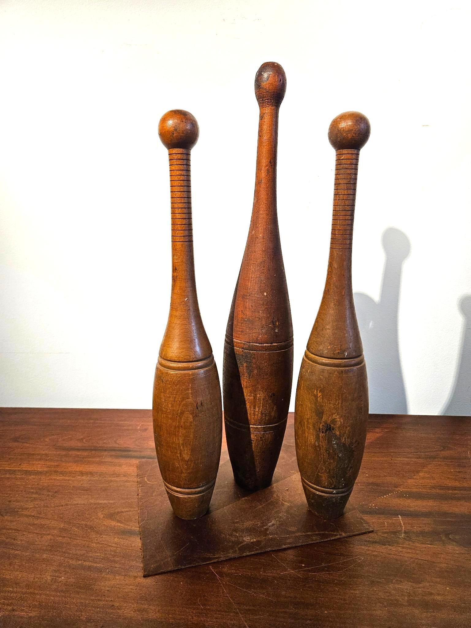 3 Indian Hardwood Exercise Clubs: This set consists of three hand-turned hardwood exercise clubs, commonly known as Indian clubs, used for physical conditioning. The collection features one tall central club and two smaller matched cl