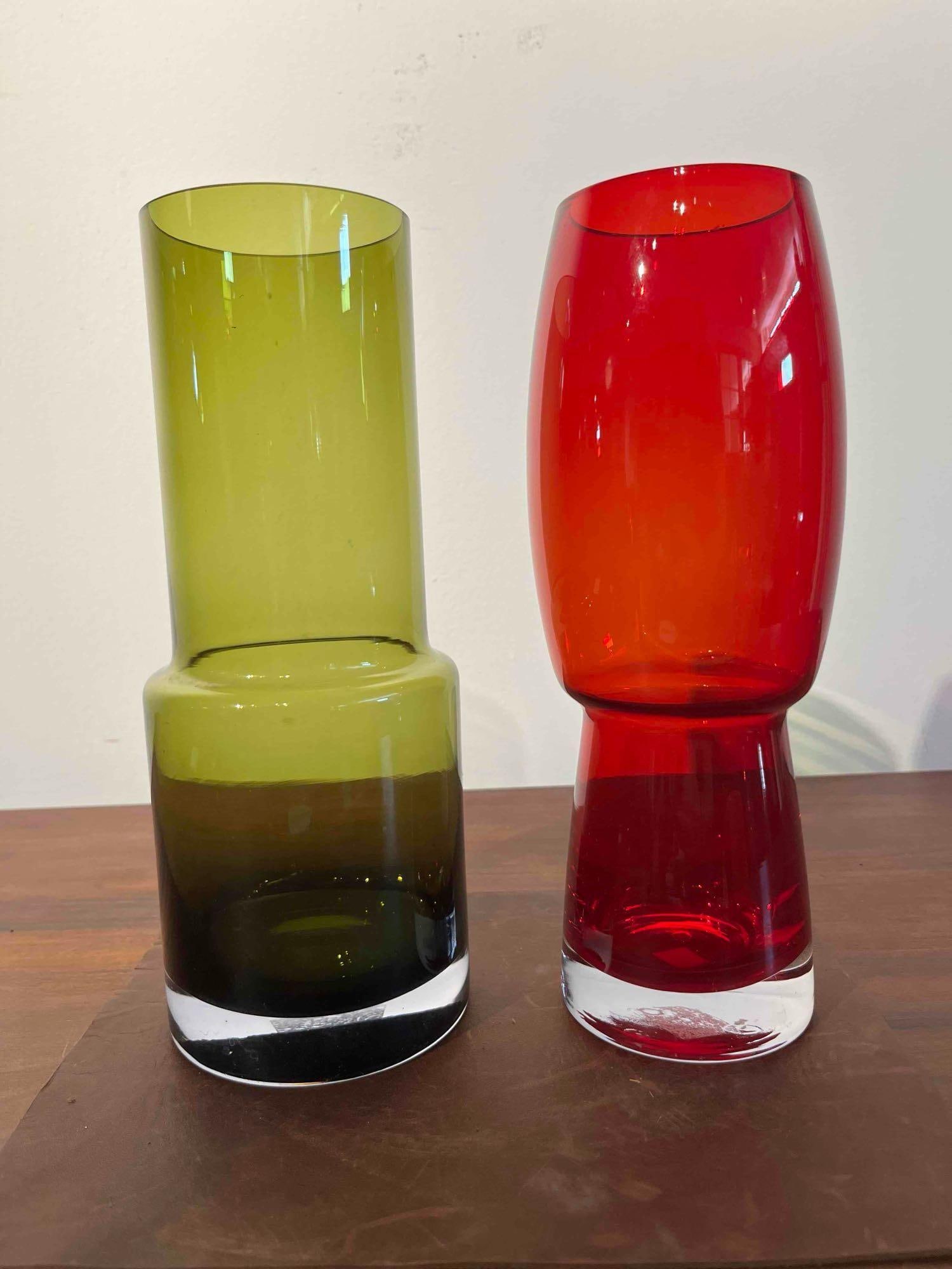 Pair Mid-Century Modern Art Glass Vases: This set consists of two hand-blown art glass vases featuring bold mid-century modern silhouettes. The first vase is finished in olive green glass with a stepped cylindrical form consisting of a narro