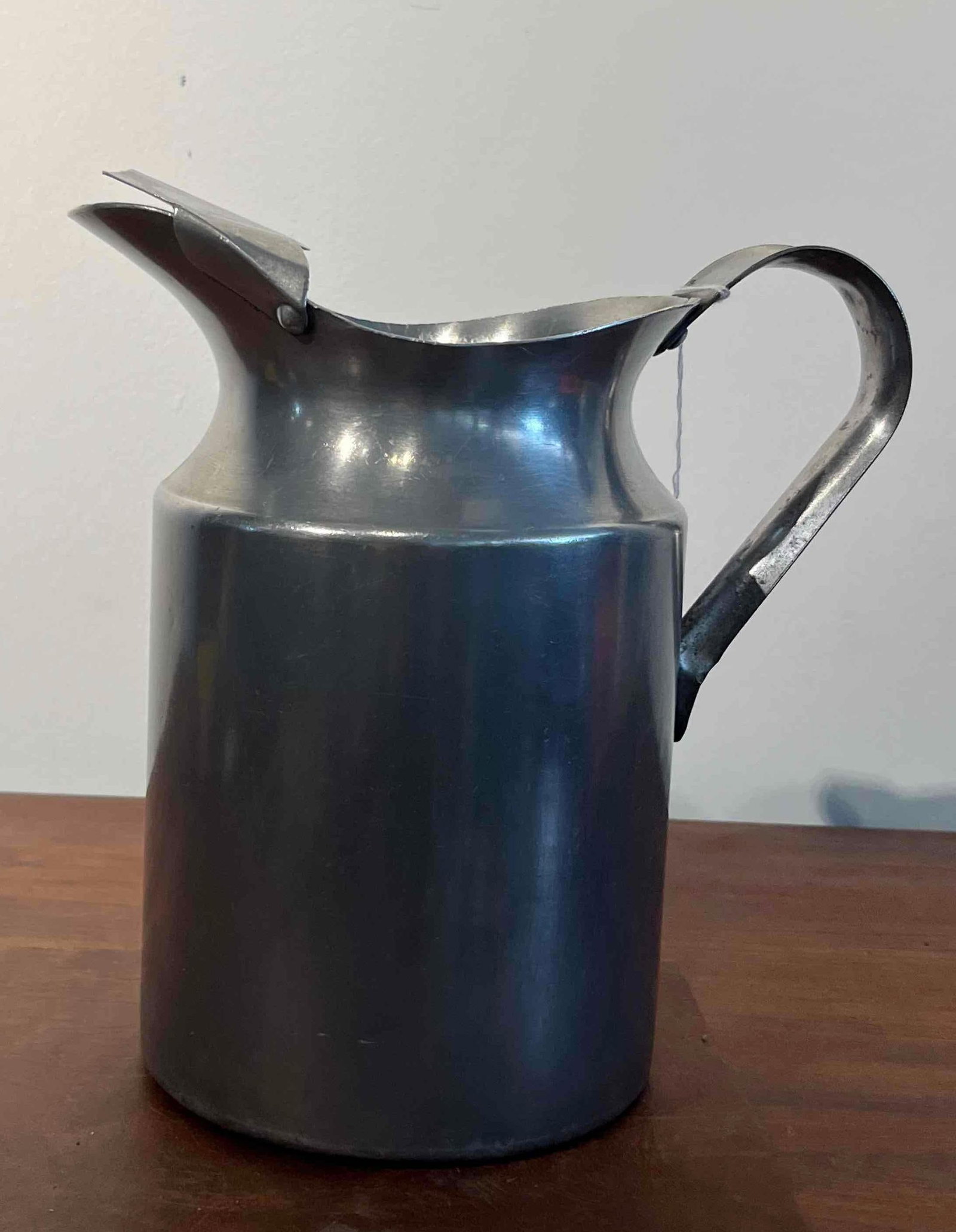 Walker Aluminum Pitcher w/ Ice Guard: This mid-twentieth century American aluminum pitcher features a spun cylindrical body that tapers toward the neck and flares into a wide rim with a pinched pouring spout. An integrated scalloped ice g