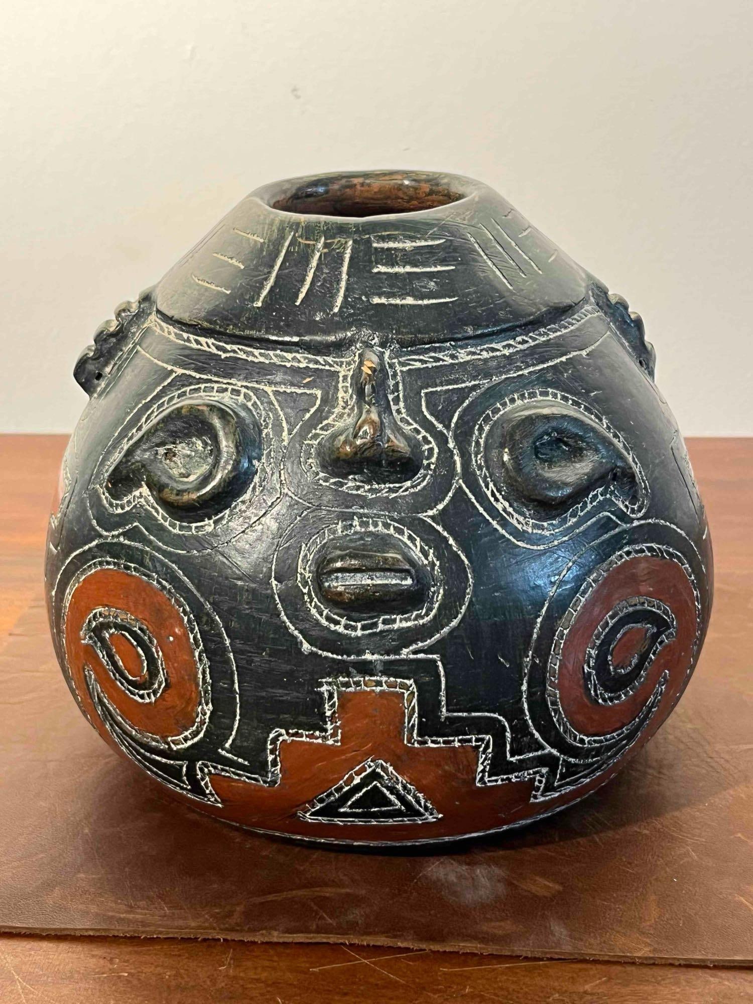 Alcides Neo-Pre-Columbian Face Vessel: A hand-built South American earthenware vessel featuring Neo-Pre-Columbian styling. The globular piece is finished with a dark green or black slip coating and decorated with four stylized anthropomorp
