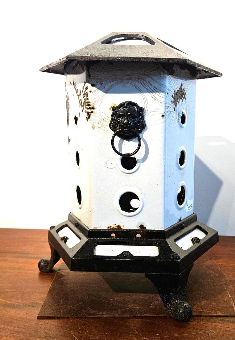 Schneider & Trenkamp Cast Iron Heater: This portable heater features a hexagonal tower form constructed from enameled steel panels set between a vented cast iron top and a tripod cast iron base. The white enameled body is pierced with thre