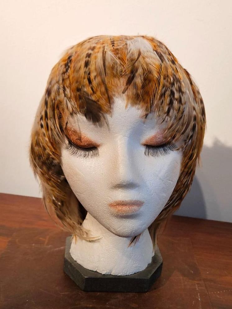 Pheasant Feather Bob Headpiece: A millinery headpiece or feather wig designed to resemble a short bob haircut with straight bangs. The piece is composed of natural bird feathers, including pheasant plumage, in a multi-tonal palette