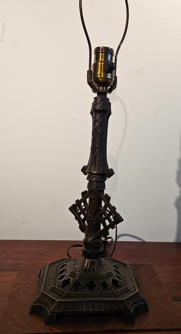 Art Deco Cast Metal Table Lamp Base: A table lamp base constructed from cast metal with a dark bronze-toned patinated finish. The central shaft features a series of geometric architectural collars and a prominent openwork diamond-lattice