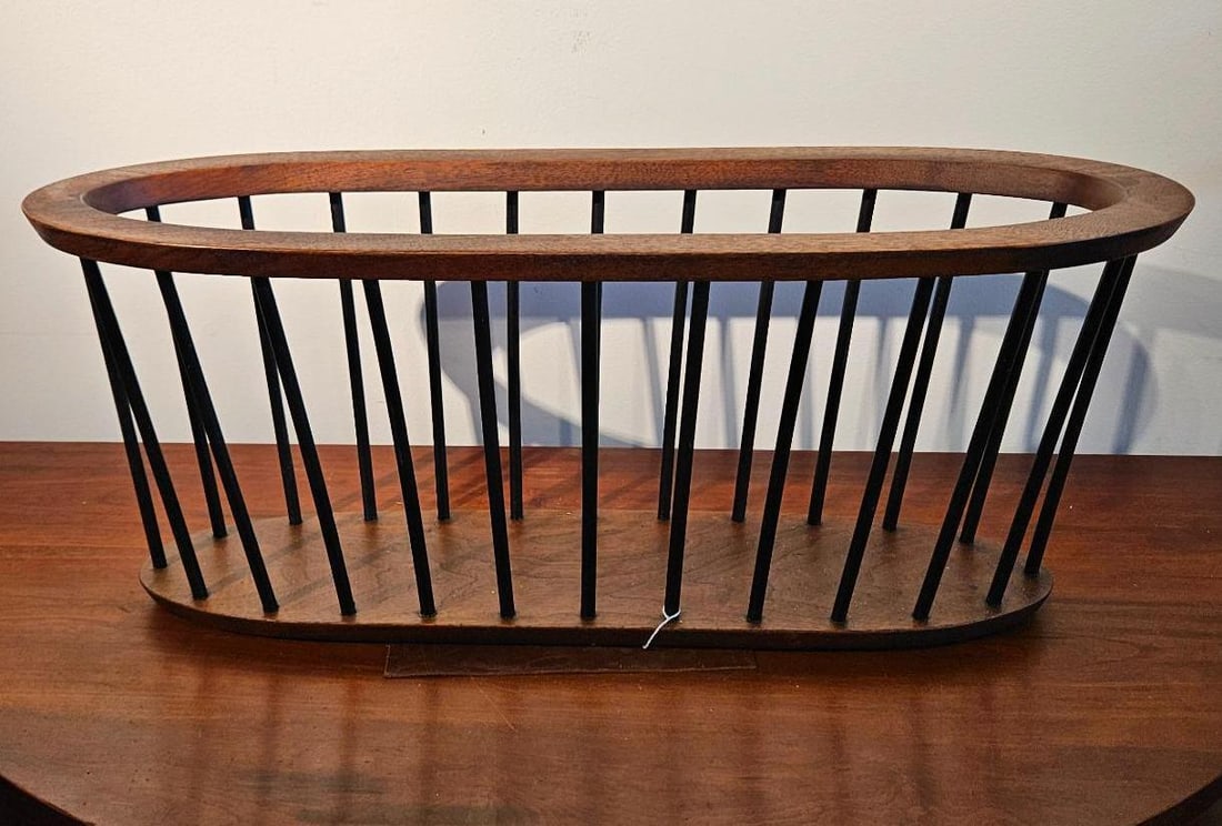 Mid-Century Wood & Metal Spindle Rack: A large floor-standing mid-century modern magazine rack constructed with a solid wood base and matching top rim in a walnut finish. The elongated oval frame is joined by twenty-eight slender,