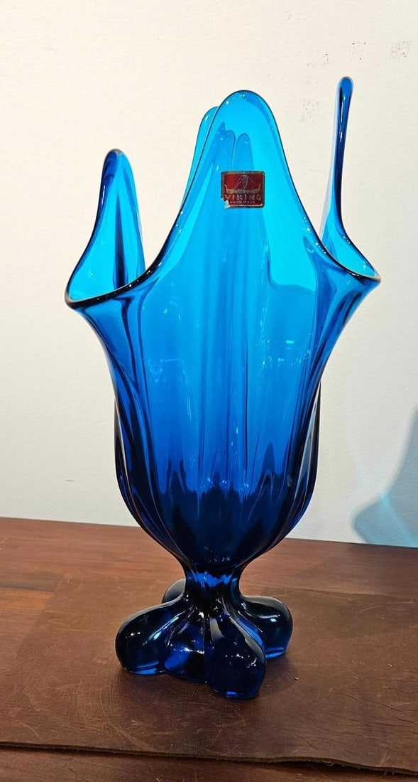 Viking Glass Bluenique Epic Swung Vase: A mid-century modern swung art glass vase produced in a vibrant blue color known as Bluenique. The vessel features a four-lobed pedestal base and a body with molded vertical ribbing that tapers slight