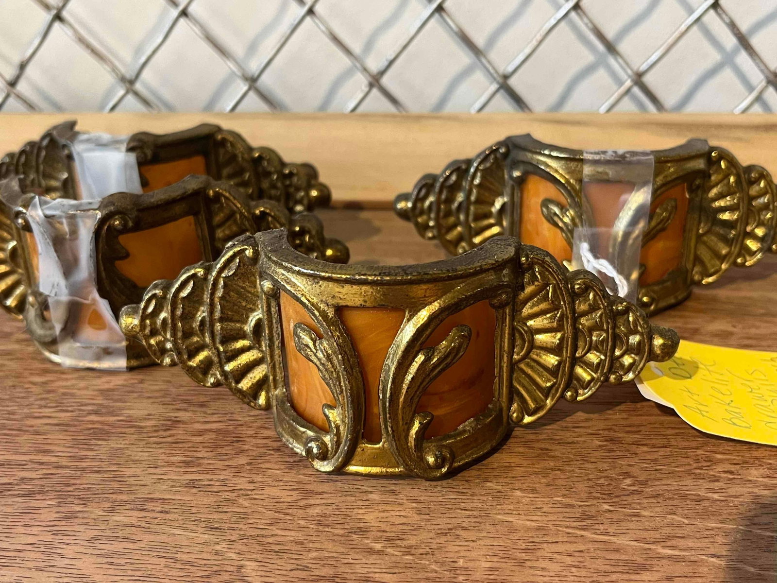 Trio Art Deco Bakelite Waterfall Pulls: A trio of Art Deco period drawer pulls, characteristic of the Waterfall furniture style popular in the 1920s and 1930s. Each pull features a cast metal housing with a gold-tone finish, designed with