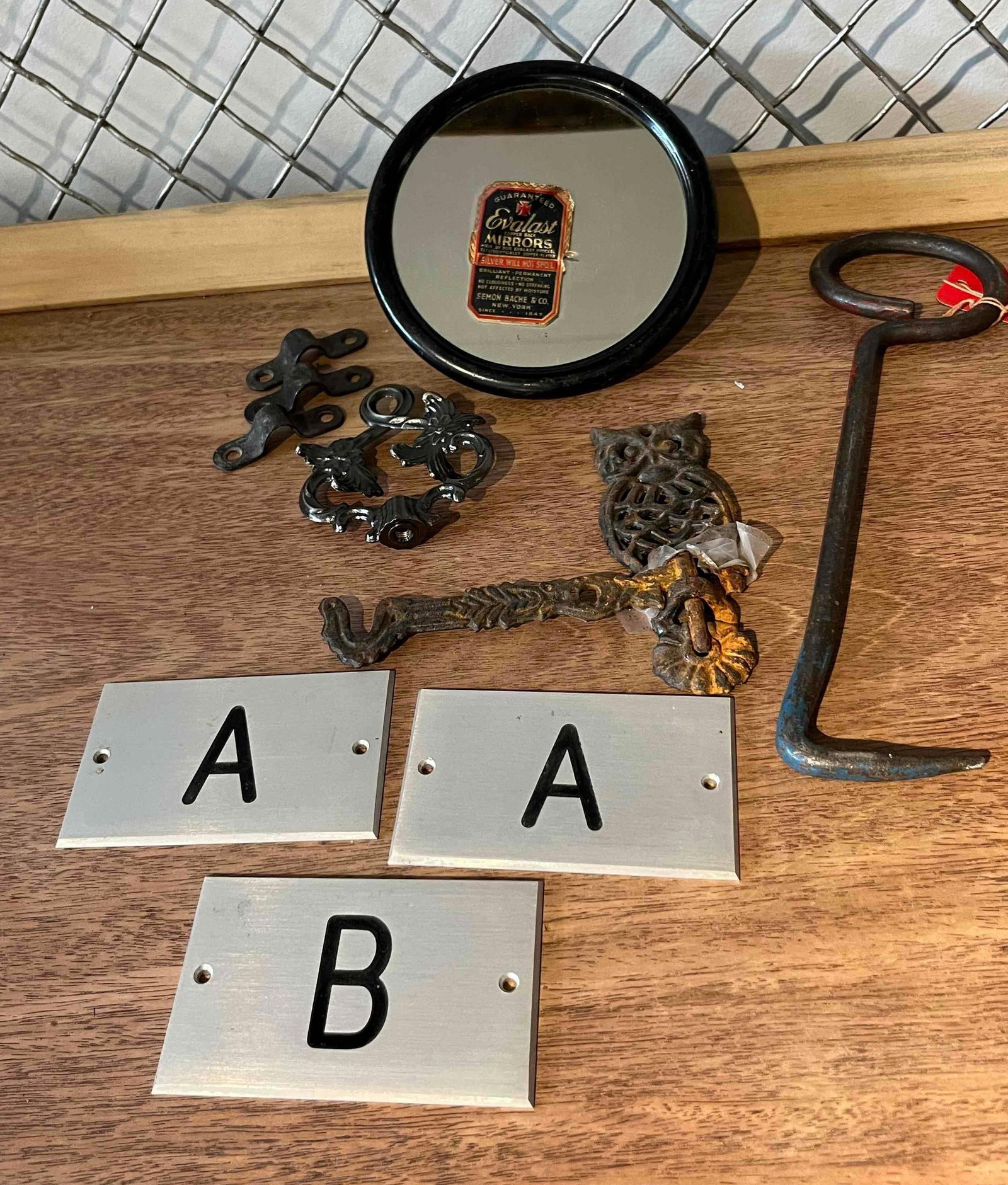 Evalast Mirror, Iron Salvage & Hardware: This assortment of architectural salvage and hardware includes components of varying materials and periods. A small round automotive mirror features an adhesive foil label on the glass reading in