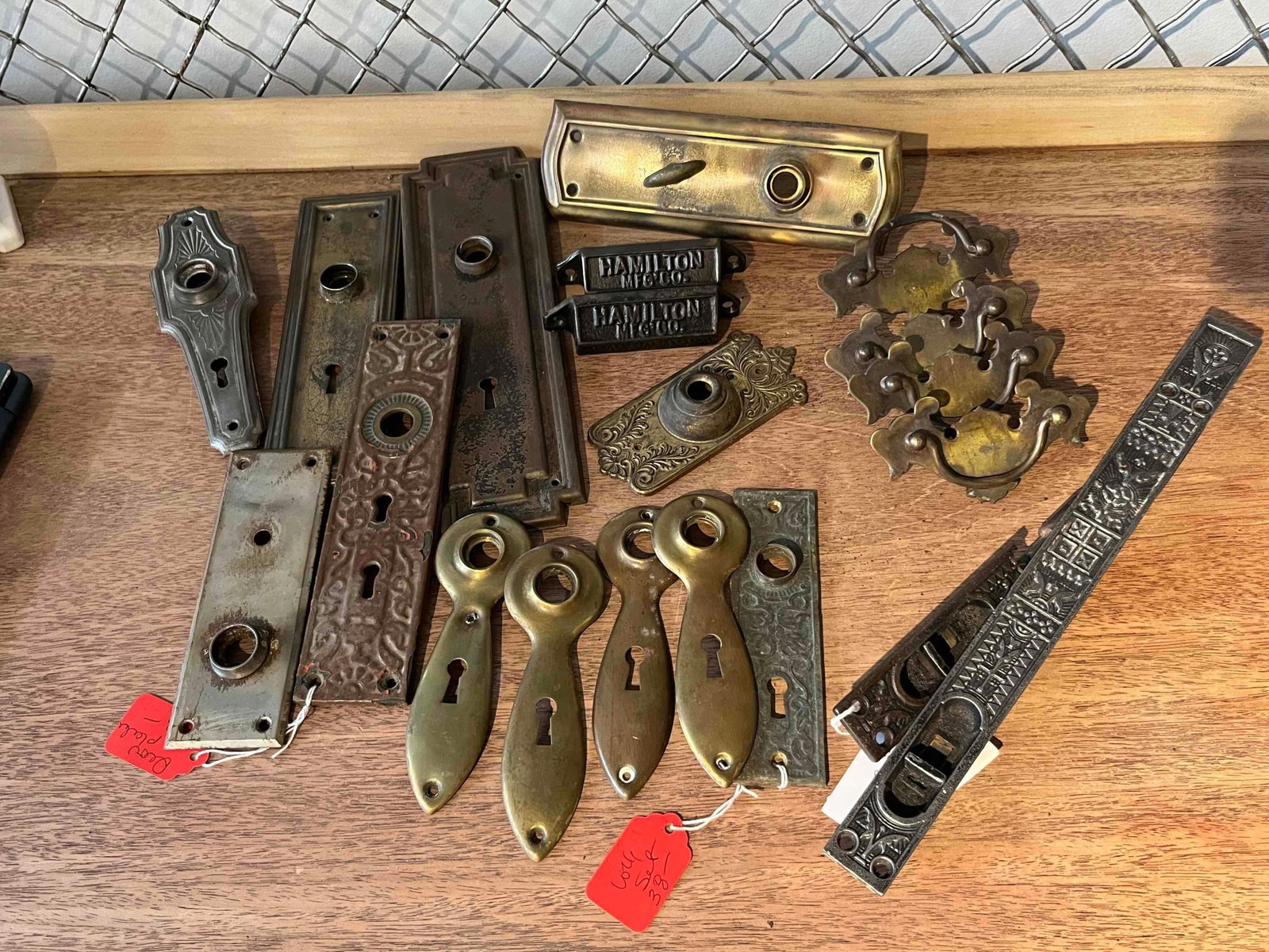 Hamilton Mfg. Co. Pulls & Hardware Set: This lot comprises a collection of architectural and furniture hardware including drawer pulls, door plates, and escutcheons executed in various historical styles. The collection includes two cast