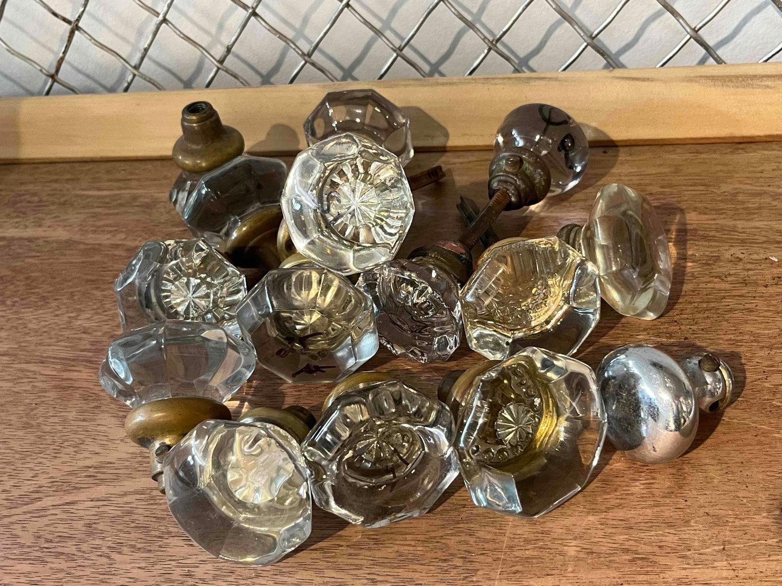 15 Molded Glass Door Knobs: A substantial lot of approximately 15 door knobs representing American residential hardware from the late 19th to early 20th centuries. The collection primarily consists of clear molded glass knobs in