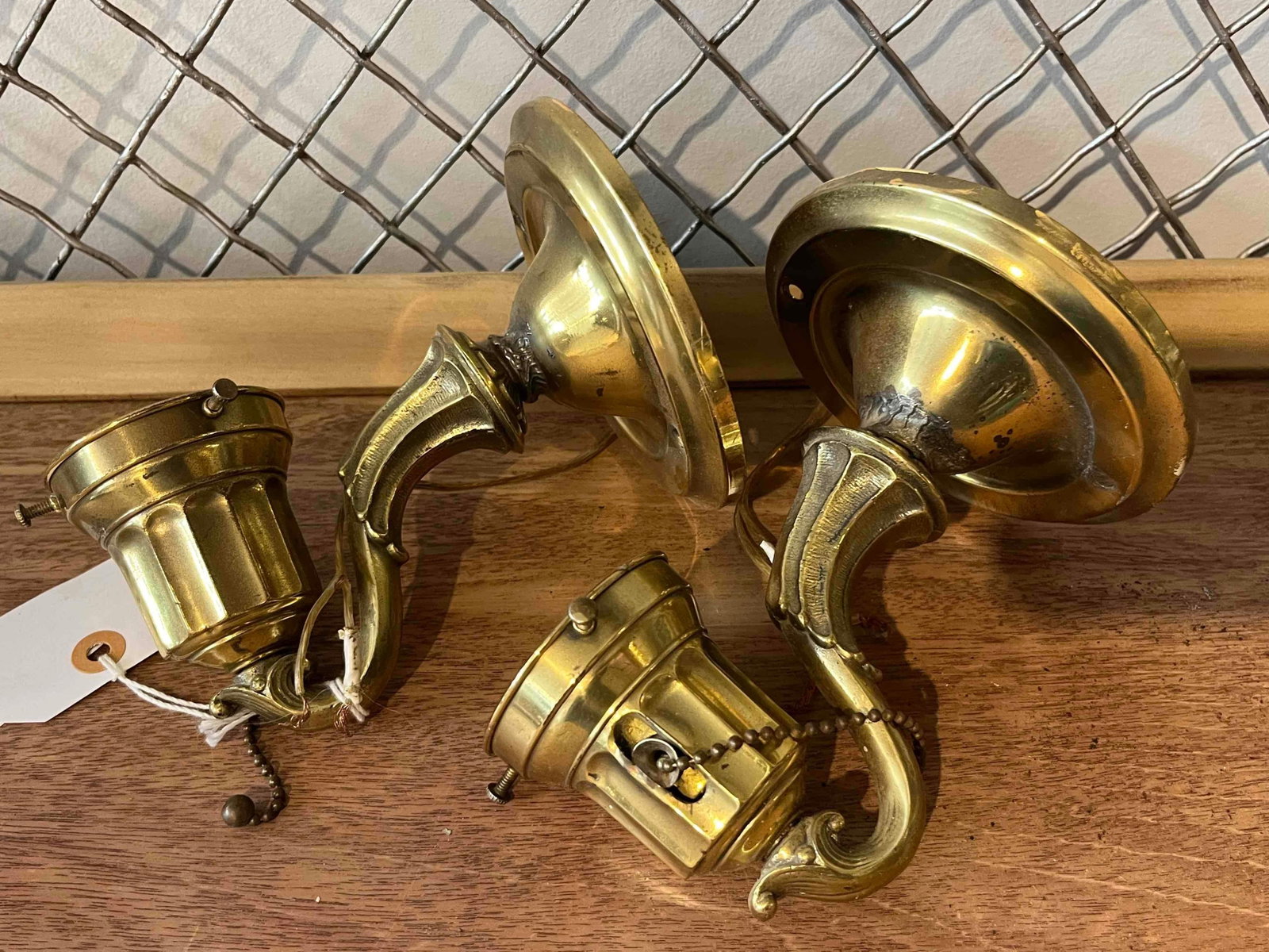 Pair Brass Wall Sconces: This pair of wall sconces is constructed from cast and stamped brass components. Each fixture features a circular, stepped backplate with three pre-drilled mounting holes. The backplate supports a