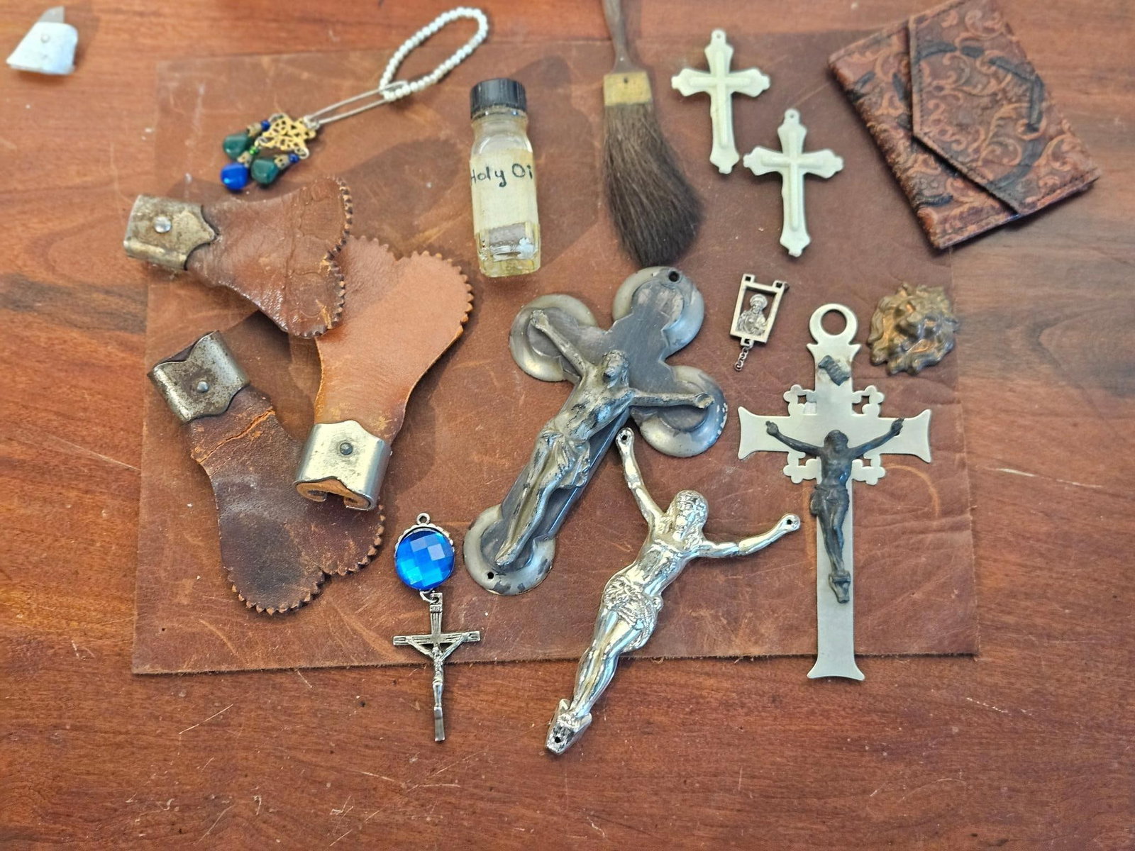 Religious & Liturgical Artifacts: This assortment of devotional and liturgical objects includes several crucifixes constructed from silver-toned metal, brass-toned metal, and white celluloid. The collection features a clear glass bott