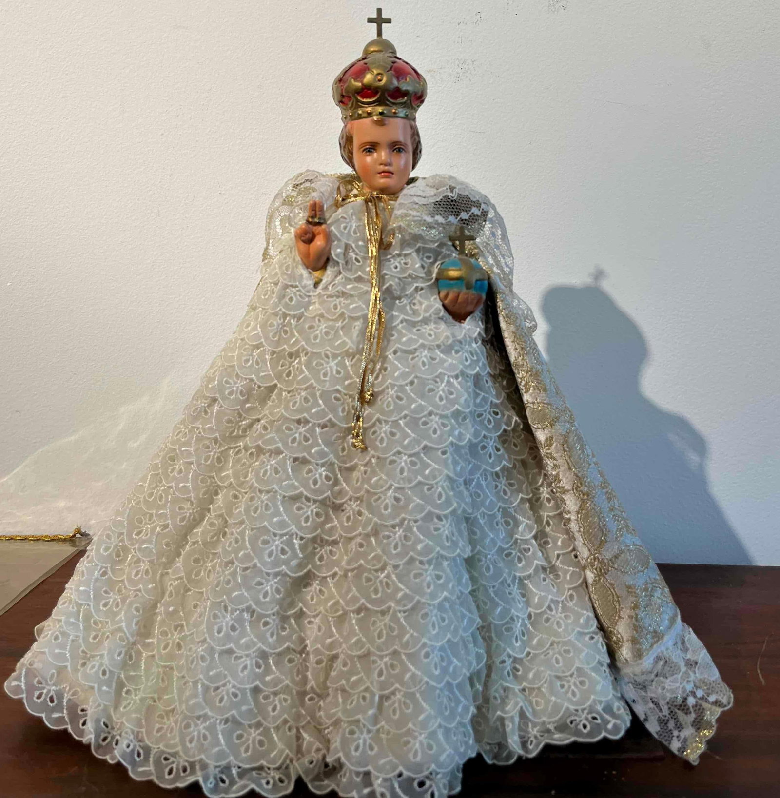Infant Jesus of Prague Figurine w/ Dome: A religious figurine depicting the Infant Jesus of Prague, presented in ceremonial attire and accompanied by a protective display dome. The figure is modeled with a painted composition or chalkware he