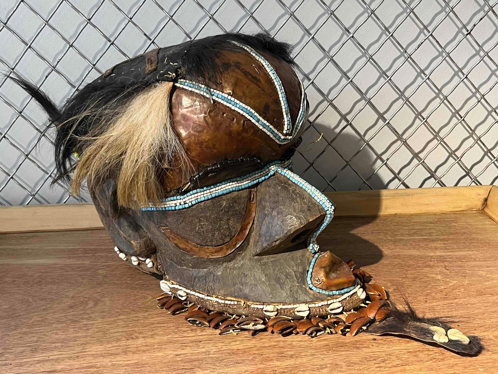 Kuba Bwoom Royal Helmet Mask: This mixed-media helmet mask represents the Bwoom character of the Kuba people from the Democratic Republic of the Congo. It is constructed from a hand-carved wooden face and ears, with the forehead a