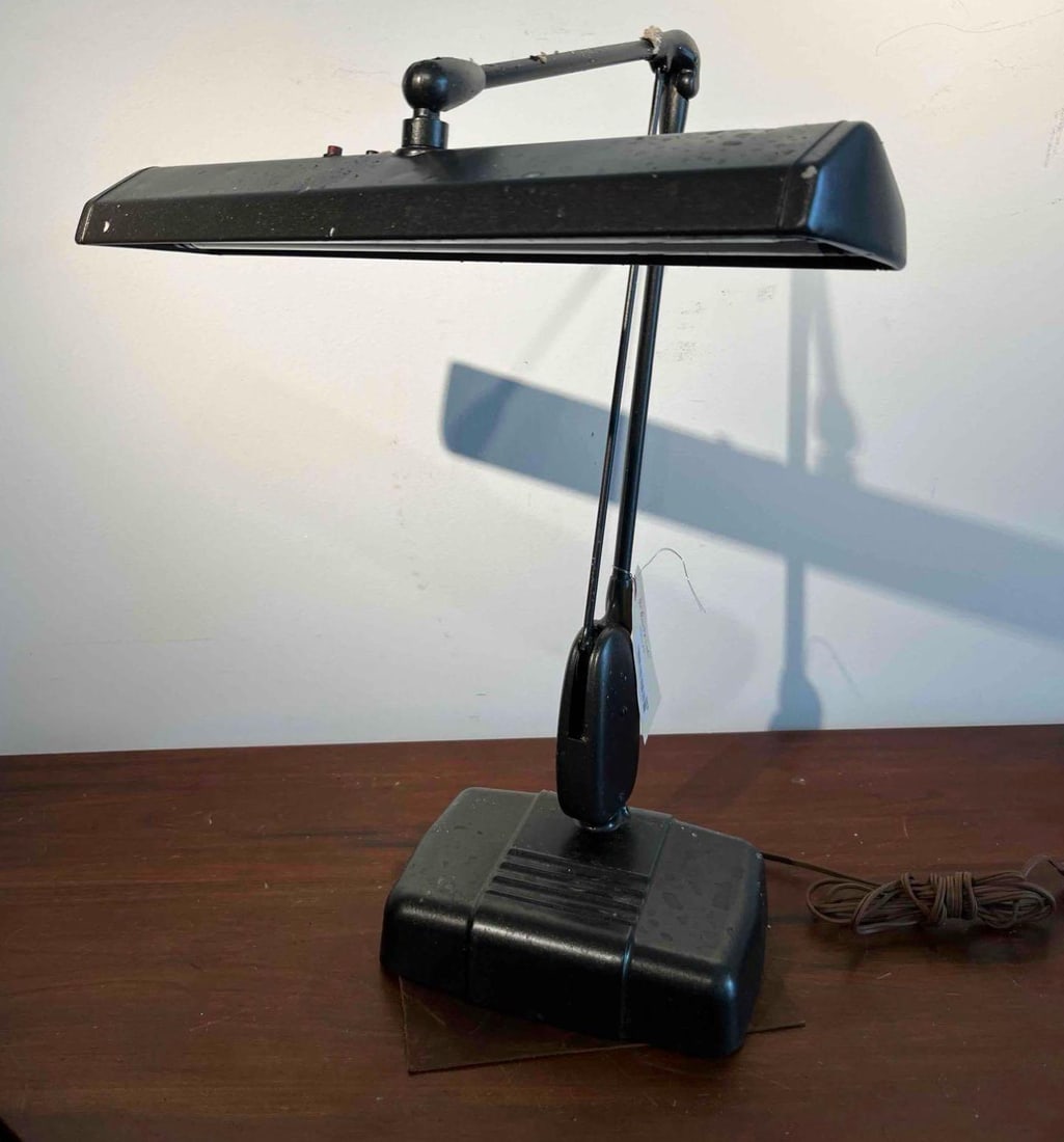 Industrial Articulating Desk Lamp: This industrial desk lamp is constructed from black-finished metal and features a weighted, stepped rectangular base. The articulating arm consists of a dual-rod mechanism designed for adjustable posi