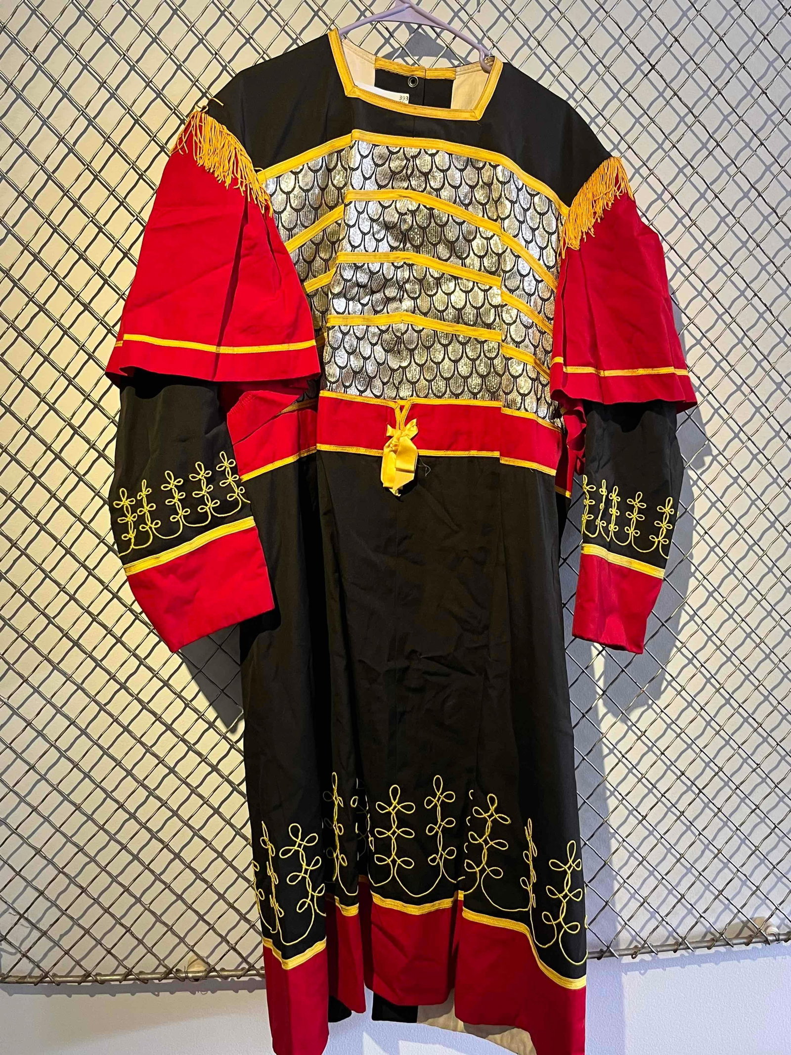 Roman Military Tunic w/ Silver Scale: A full-length, long-sleeve costume tunic designed with a Roman military aesthetic. The garment is constructed from black and red woven fabric, likely a synthetic or cotton blend. The bodice and back f