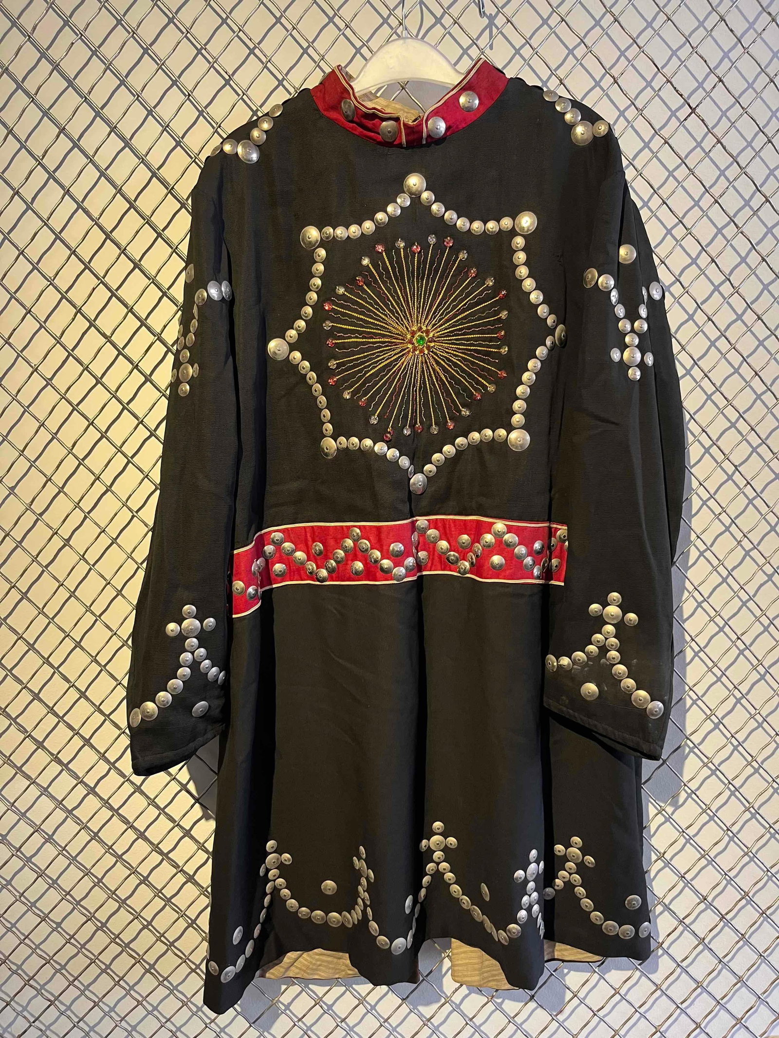 M.C. Lilley & Co. Fraternal Tunic: This long black ceremonial tunic was manufactured by The M.C. Lilley & Co. in Columbus, Ohio. The primary body is composed of a heavy black textile with a light-colored striped fabric lining. The garm