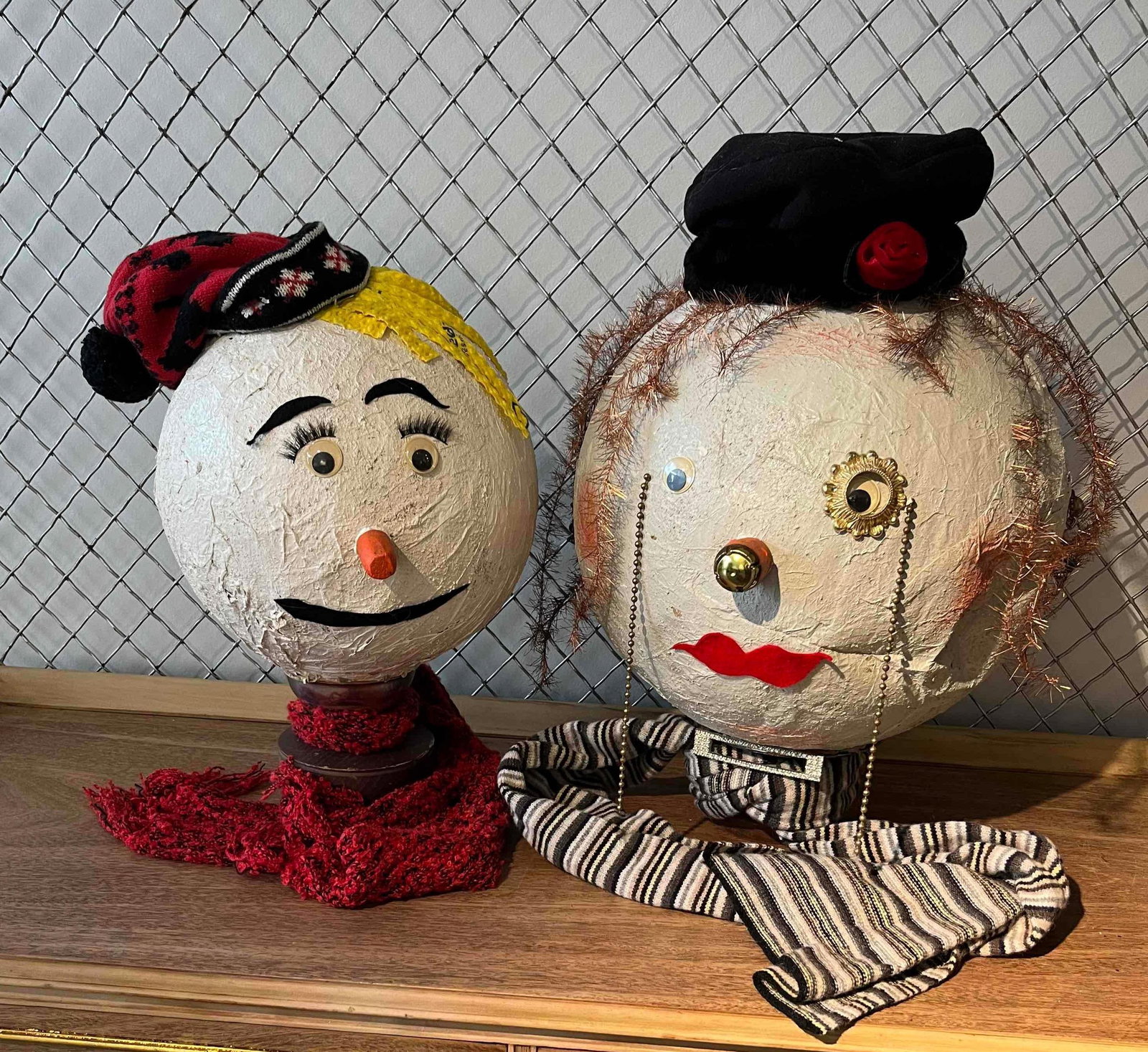 Pair Mixed Media Folk Art Snowman Heads: A pair of handcrafted, mixed-media folk art sculptures fashioned as whimsical snowman-style heads. The primary forms are large, off-white spheres with a heavily textured, plaster-like or paper-mache f